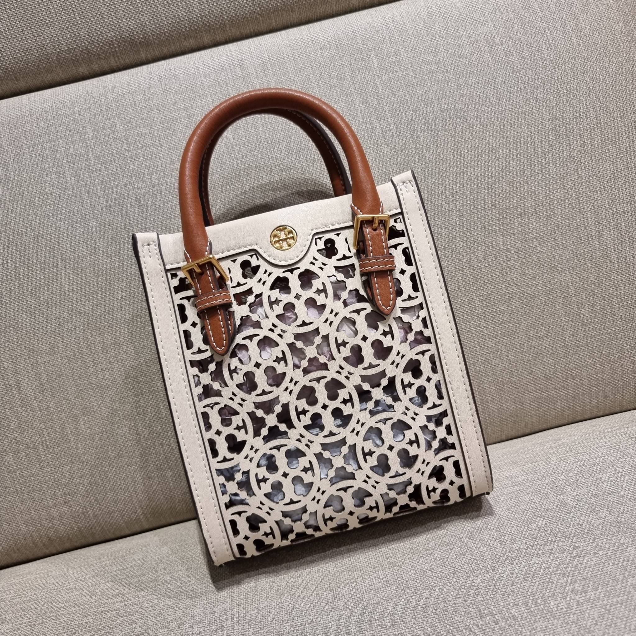 TORY BURCH T MONOGRAM LASER-CUT MINI TOTE ใจบางที่สุดกับคอลเลคชั่นนี้ กับกระเป๋าสะพายทรงโท้ท ไซส์มินิ ที่เพิ่มดีเทลความแพงด้วยการฉลุลวดลายโมโนแกรมรอบใบ ถักทอเป็นเส้นลายสานที่สวยงามมาก งานฝีมือจริงๆ วัสดุหนัง cowhide ปากกระเป๋ามีแถบแม่เหล็กกันหล่น และมีหูจ
