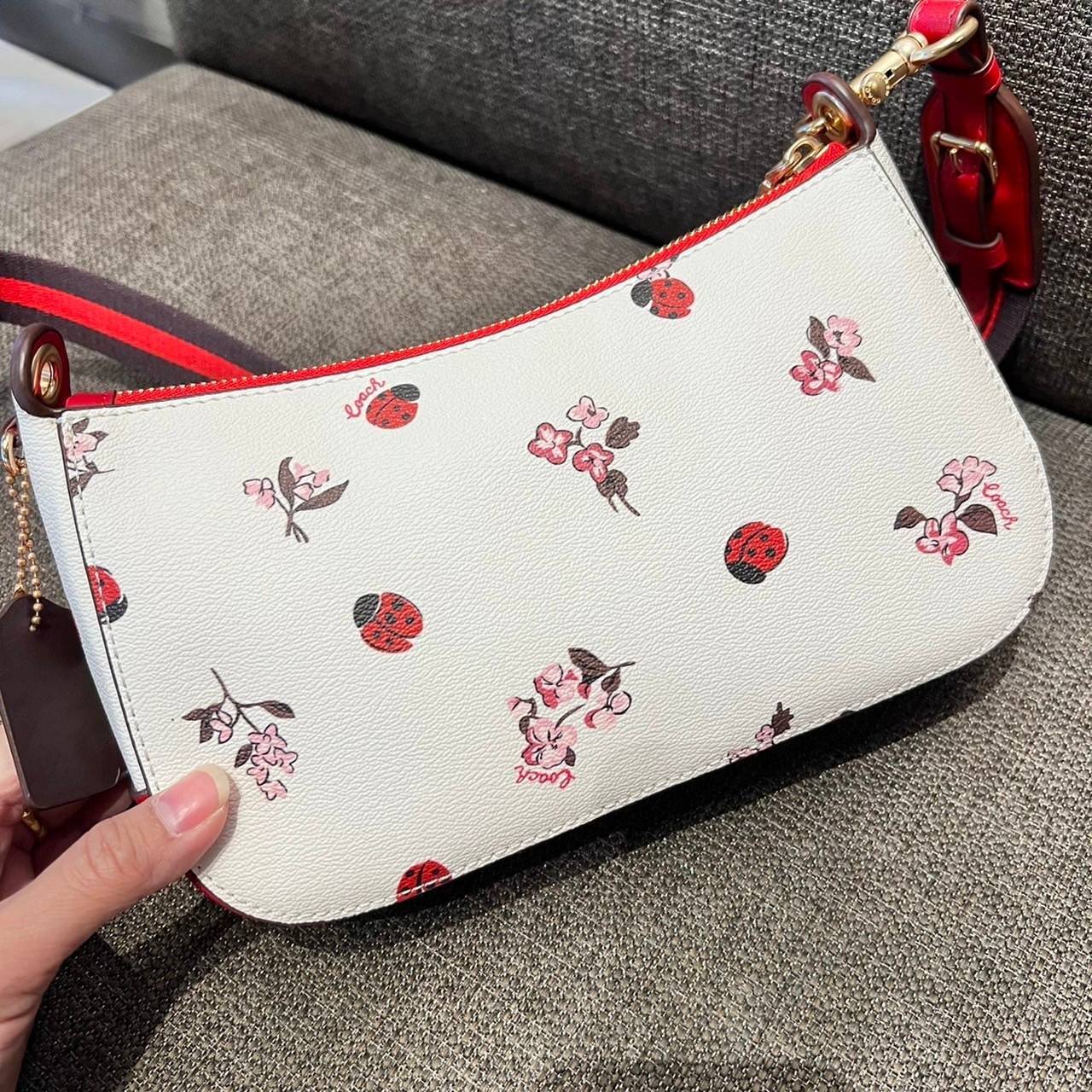 COACH C7973 JES BAGUETTE WITH LADYBUG FLORAL PRINT คอลเลคชั่นใหม่ล่าสุด พร้อมเสิร์ฟความสวยถึงบ้านเช่นเคย!! กระเป๋าสะพายทรงบาแกตต์ ดีไซน์ย้อนยุค ที่แอบแฝงความเรียบหรูดูแพงอยู่ในตัว โดดเด่นด้วยสายสะพายเส้นใหญ่ โทนสีคอนทราส ทำให้ไอเท็มนี้ดูมีลูกเล่นมากขึ้น ว