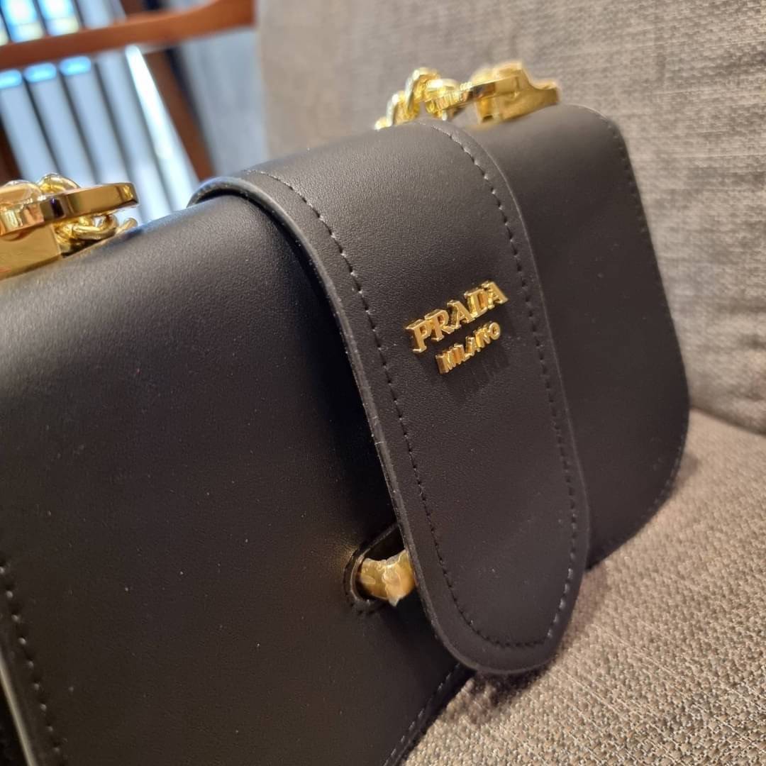 PRADA FRAGRANCE SHOULDER BAG WITH GWP ไอเท็มสุดโปรดที่ควรค่าแก่การครอบครองและเก็บสะสม กระเป๋าสะพายไหล่ สวยคม สีดำคลาสสิคตัดกับอะไหล่ทองเป็นอย่างดี วัสดุหนังแท้เต็มใบ เปิดปิดด้วยแถบหนังสอดในช่อง ใช้งานสะดวก พกพาง่าย ขนาดกำลังสวย สายสะพายในตัว สะพายได้หลากห