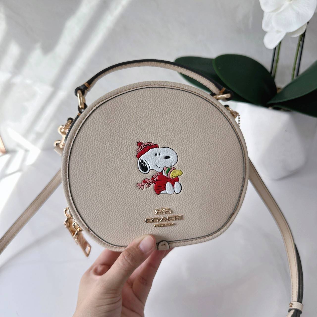 COACH X PEANUTS CANTEEN CROSSBODY WITH SNOOPY PRESENT MOTIF (CE845,CF290) กระเป๋าสะพายข้างทรงกลมไซส์มินิ มีหูจับ วัสหนังแท้ ด้านหน้าโดดเด่นด้วยรูปการ์ตูนSnoopy