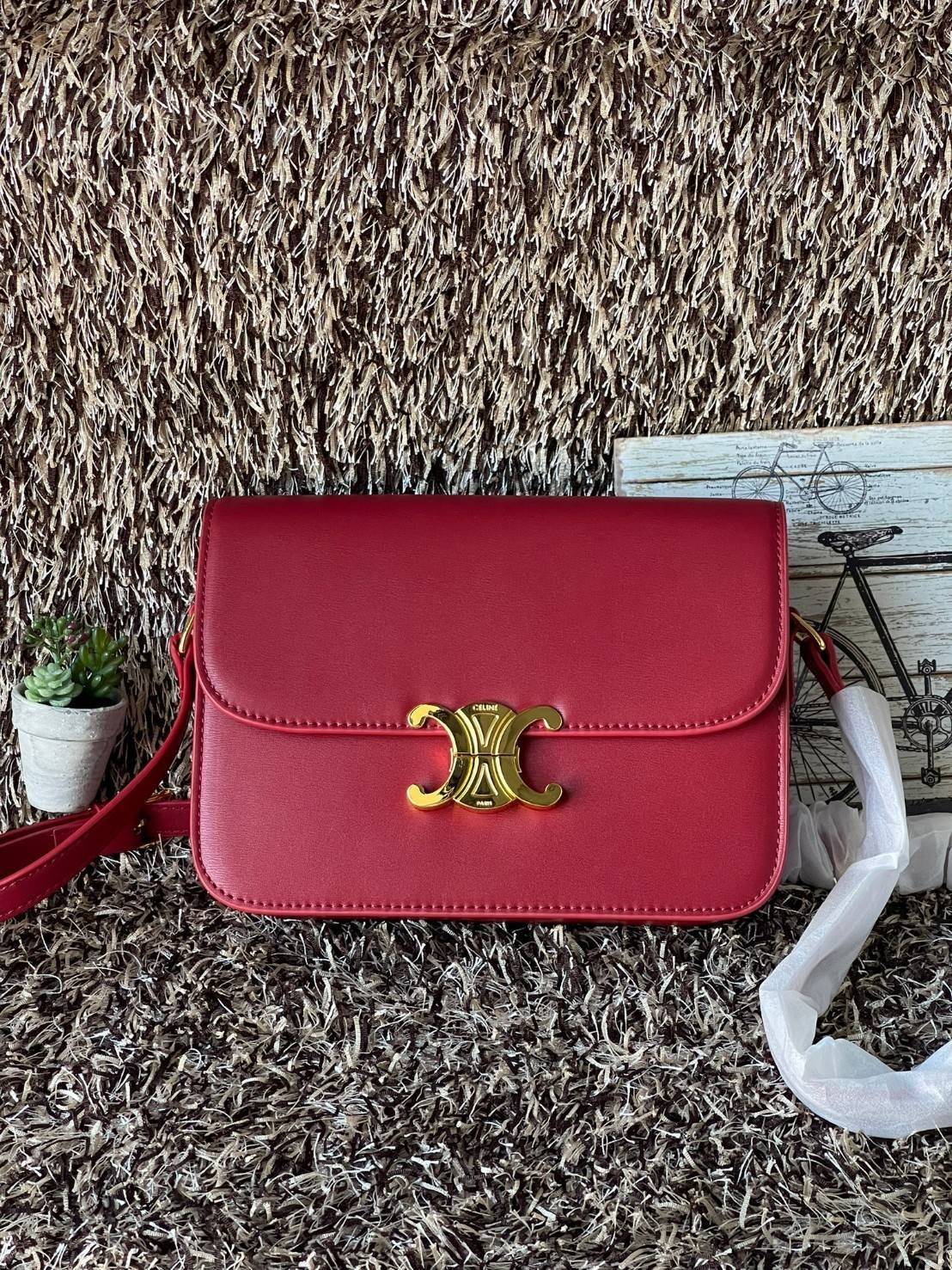 Celine MEDIUM TRIOMPHE BAG IN SHINY มีรูปทรงเป็นกล่องคล้ายกับกระเป๋า Classic Box แต่มีการออกแบบโลโก้ที่สะดุดตาแบบวินเทจ ด้วยดีไซน์ที่ดูโฉบเฉี่ยว แต่คงความคลาสสิคอย่างเต็มเปี่ยม ทำให้เป็นที่ดึงดูดความสนใจของสาวๆ สายสะพายสามารถปรับระดับได้ มีความคล่องตัวในก