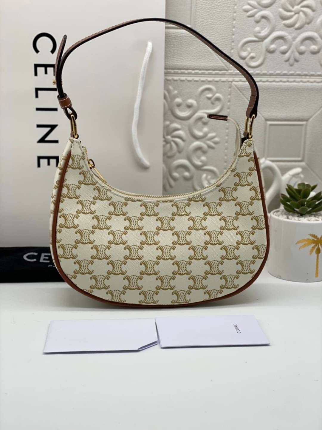 หนังแท้ CELINE AVA / CELINE Vintage Classic Ava bag 1 ใน คอลเลคชั่น “Triomphe Canvas” มาพร้อมสายสะพายไหล่ที่ปรับความยาวได้ และเนื่องจากช่วงล่างของกระเป๋ามีขนาดใหญ่กว่าช่วงบน จึงทำให้ไม่เสียทรงเมื่อเราใส่สิ่งของอย่างกระเป๋าสตางค์หรือโทรศัพท์มือถือ หากดูภาพ