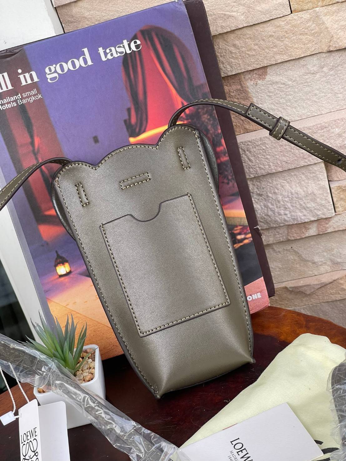 Loewe Leather Elephant Phone Holder แบรนด์หรูจากประเทศสเปนอย่าง โลเอเว่ (LOEWE) หลายๆคนคงนึกถึงกระเป๋ารูปทรงช้างขนาดเล็ก ที่เป็นเหมือนหนึ่งในซิกเนเจอร์ของแบรนด์ มีทั้งแบบสะพายข้าง แบบถือ รวมไปถึงในแบบเครื่องหนังชิ้นเล็กอย่างกระเป๋าใส่มือถือรุ่นนี้ ผลิตจาก
