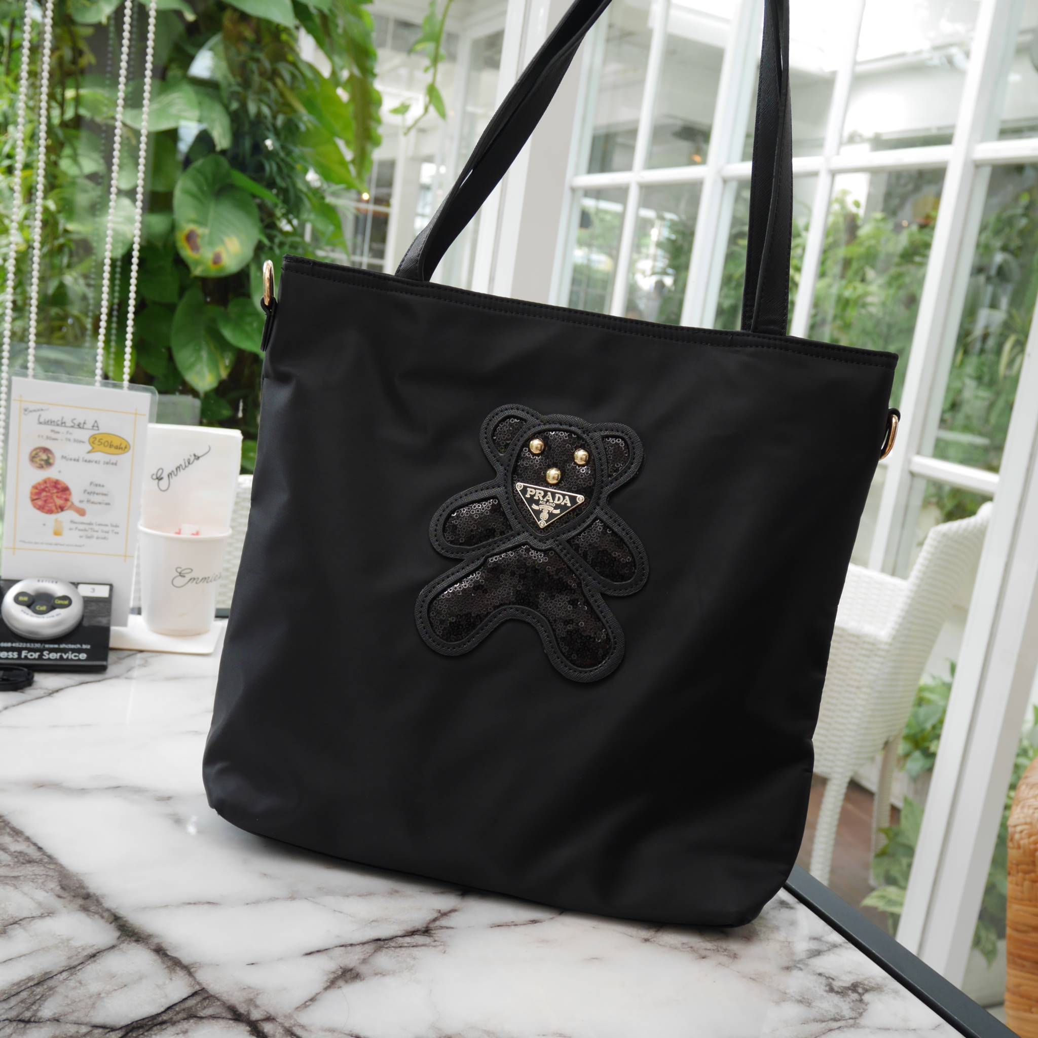 งานขายดีคะ ♡♡ กระเป๋าสะพาย ทรง TOTE จากแบรนด์ PRADA มาค่า ตัวกระเป๋าเป็น nylon ทั้งใบ สะพายเป็น shoulder bag หรือถือได้ค่ะ ด้านหน้าเป็นลายหมี ปักกลิ้ตเตอร์ + logo brand ใช้แล้วสวยมากๆ อะไหล่ทองหรูมาก จุของคุ้ม ใส่หนังสือ หรือ MacBook ได้ค้า 