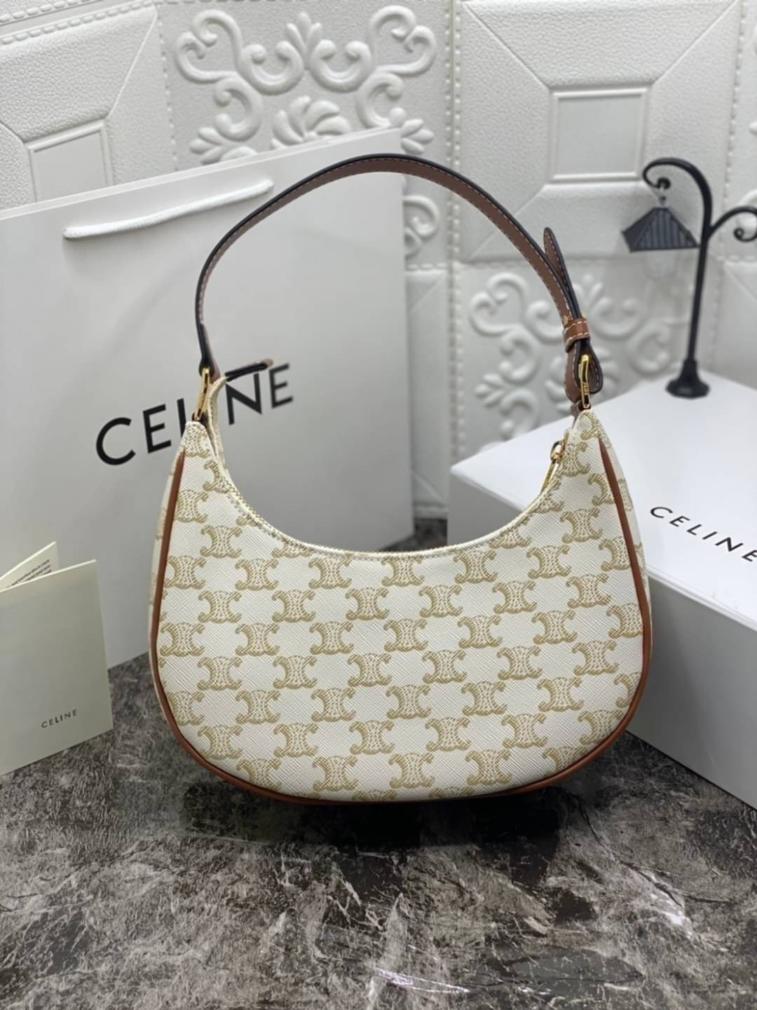 หนังแท้ CELINE AVA / CELINE Vintage Classic Ava bag 1 ใน คอลเลคชั่น “Triomphe Canvas” มาพร้อมสายสะพายไหล่ที่ปรับความยาวได้ และเนื่องจากช่วงล่างของกระเป๋ามีขนาดใหญ่กว่าช่วงบน จึงทำให้ไม่เสียทรงเมื่อเราใส่สิ่งของอย่างกระเป๋าสตางค์หรือโทรศัพท์มือถือ หากดูภาพ