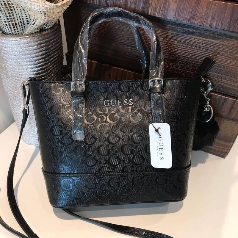 GUESS MINI CROSS BODY BAG กระเป๋าถือหรือสะพายรุ่นฮิตและขายดีที่สุดจาก GUESS FACTORY วัสดุหนังแก้วเงาสวยอยู่ทรง น้ำหนักเบา ด้านหน้าประดับด้วยโลโก้แบรนด์สุดหรูพร้อมปอมๆห้อยที่หูกระเป๋าถอดเเยกใช้ได้ เปิดปิดกระเป๋าด้วยซิปสะดวกใช้ ด้านในโล่งกว้างมีช่องซิปและช่