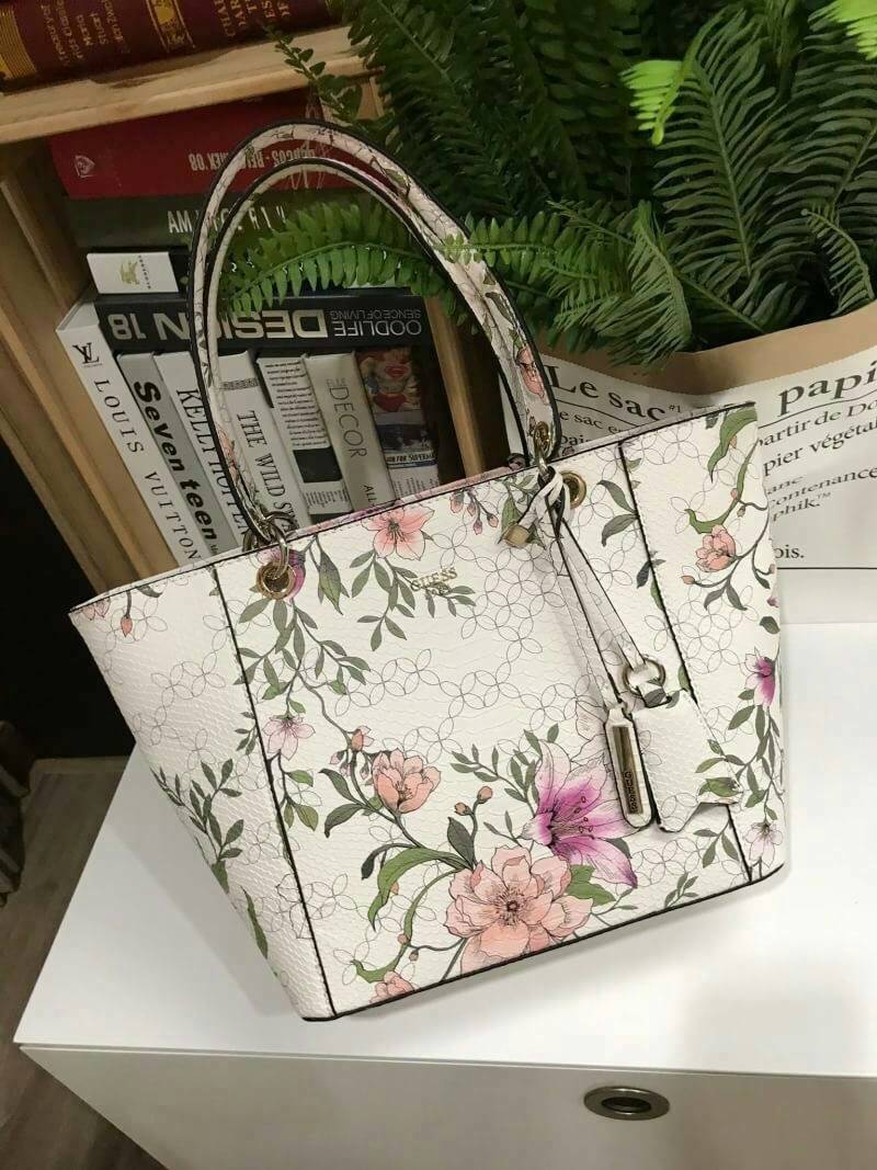 GUESS PRINTED KAMRYN FLOWERS SHOPPER BAG (SIZE L) กระเป๋าสะพายจาก GUESS FACTORY หนังสวยอยู่ทรงปริ้นลายดอกไม้คอลเลคชั่นล่าสุดใบใหญ่กำลังดี ใส่สัมภาระได้จุใจ น้ำหนักเบา ด้านหน้าประดับโลโก้แบรนด์อะไหล่เงินพร้อมพวงกุญแจแบรนด์ห้อยที่หูหิ้วถอดเเยกใช้ได้ หูหิ้วพ