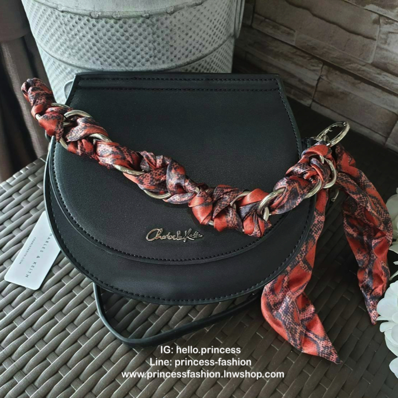 CHARLES & KEITH รุ่น LEATHER SATIN SCARF CROSSBODY BAG SL2-50150828 ราคาปกติช้อป ( ฿3,590.00 ) กระเป๋าถือ และ สะพาย ทรงโค้งมน หนังเรียบ ตั้งอยู่ทรง ด้านหน้าติดโลโก้แบรนด์ อะไหล่เงิน หูจับสายกระเป๋าร้อยเข้ากับห่วงเหล็กกลมๆ ด้วยผ้าลายสวยงามผูกเป็นโบว์เก๋ๆ ถ