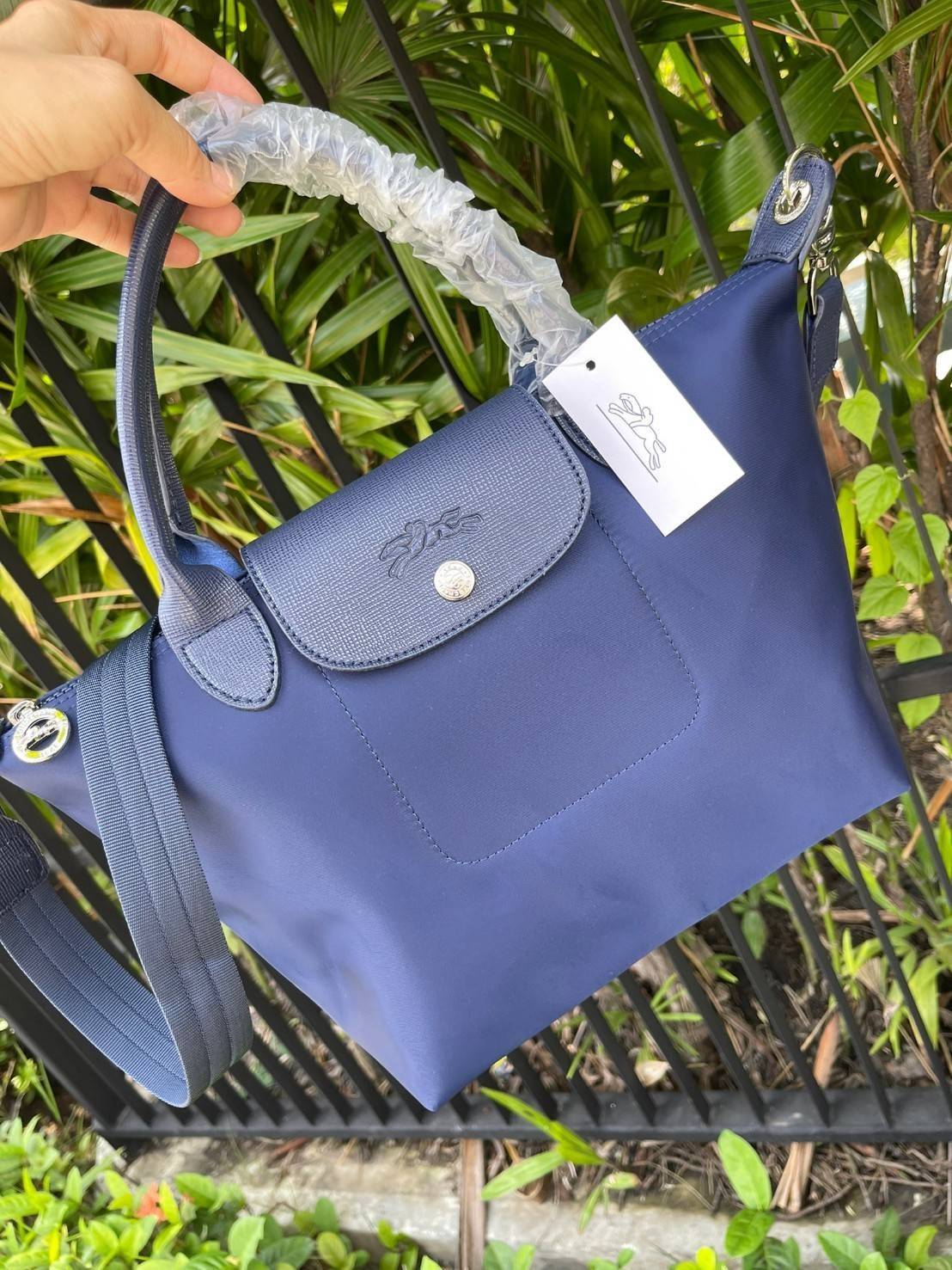 Longchamp Le Pliage Neo Size S มาพบกับกระเป๋ารุ่นยอดนิยม ที่สาวๆ ต้องมีไว้เก็บไว้สักใบ กระเป๋าโท้ทใบนี้ มาพร้อมกับสีที่มีสไตล์เรียบง่าย มีสายสะพายยาวช่วยให้คุณสามารถสะพายไหล่ได้อย่างสบาย ในขณะที่ที่ปิดแบบซิปช่วยให้คุณมั่นใจได้ว่าของด้านในมีความปลอดภัย Le 
