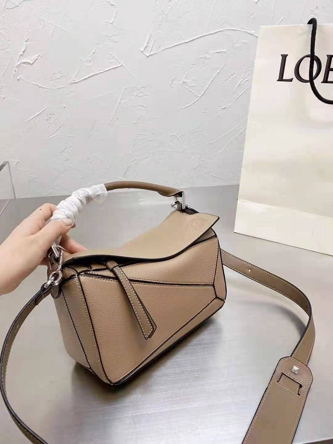 Loewe Puzzle Bag In Classic กระเป๋าทรง Puzzle นี้ออกแบบโดย Jonathan Anderson โดยได้รับแรงบันดาลใจในการออกแบบมาจากรูปทรงของลูกรักบี้ ดังนั้น จึงจะเห็นได้ว่าการตัดเย็บและรูปทรงของกระเป๋านั้นคล้ายคลึงกับลูกรักบี้ รูปทรงดูมินิมอลไม่ทิ้งคอนเซ็ปต์ของแบรนด์ สามา