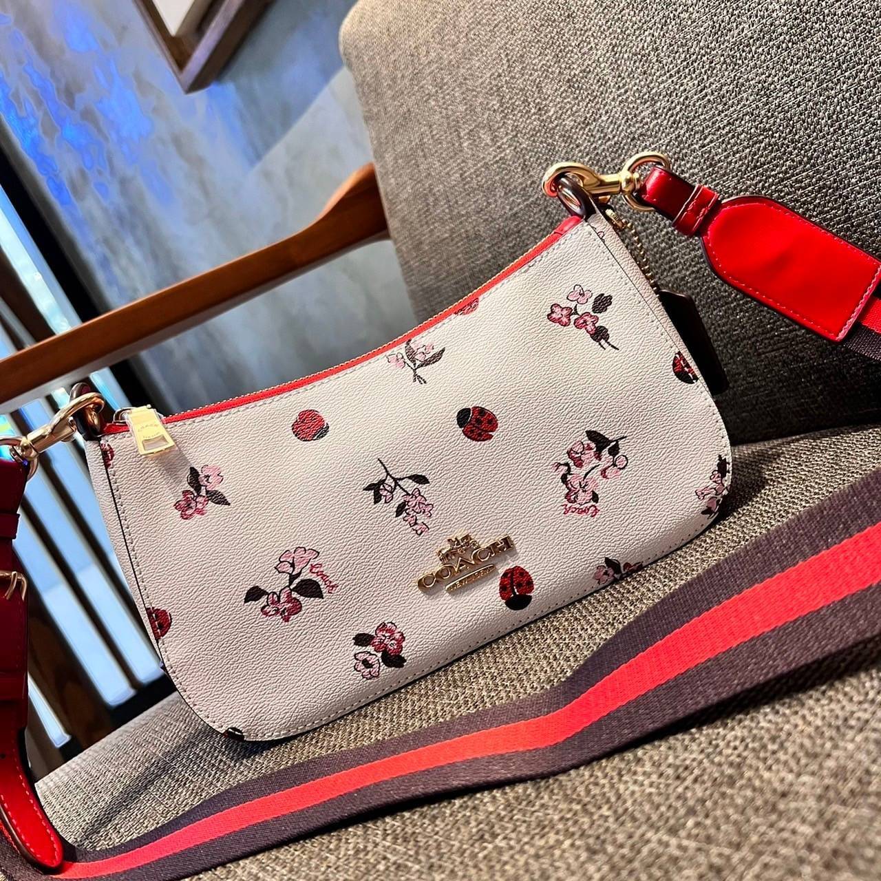 COACH C7973 JES BAGUETTE WITH LADYBUG FLORAL PRINT คอลเลคชั่นใหม่ล่าสุด พร้อมเสิร์ฟความสวยถึงบ้านเช่นเคย!! กระเป๋าสะพายทรงบาแกตต์ ดีไซน์ย้อนยุค ที่แอบแฝงความเรียบหรูดูแพงอยู่ในตัว โดดเด่นด้วยสายสะพายเส้นใหญ่ โทนสีคอนทราส ทำให้ไอเท็มนี้ดูมีลูกเล่นมากขึ้น ว