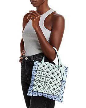 Baobao Issey Miyake Prism Kangaroo tote bag กระเป๋าถือทรงโท้ทที่ประดิษฐ์ขึ้นอย่างเชี่ยวชาญในญี่ปุ่น มาพร้อมแผงเรขาคณิตสำหรับการออกแบบที่ได้รับแรงบันดาลใจจากกระดาษพับ ซิลลูเอทอันเป็นเอกลักษณ์นี้ปิดท้ายด้วยสายรัดแบบอสมมาตร มีการพัฒนาโครงสร้างทรงสามเหลี่ยมเพ