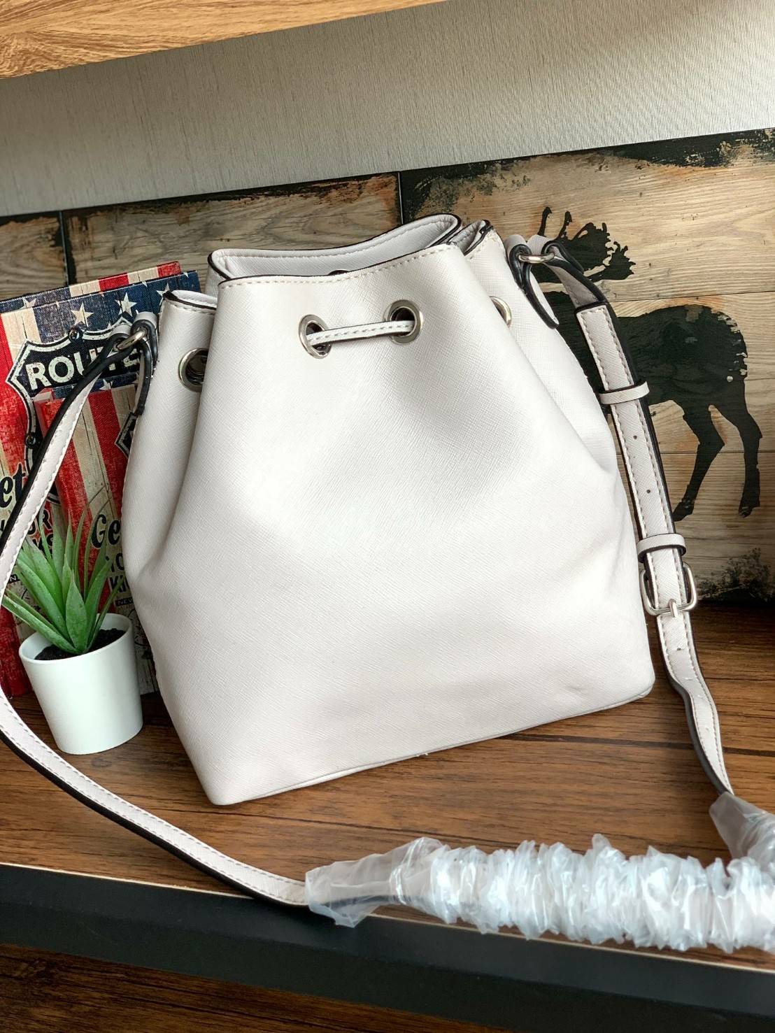 Guess Drawstring Bucket Bag กระเป๋าสะพายขนาดกลาง วัสดุลายหนังsaffiano ฐานกว้างตั้งอยู่ทรง มีซิกเนเจอร์ที่ด้านหน้าเป็นโลโก้ตัวนูน เปิดปิดแบบหูรูดและกระดุมแม่เหล็ก มีช่องใช้งานหลายข่อง สายสะพายปรับได้แบบเข็มขัด สวยแบบมีดีเทลเก๋ๆ สะพายเที่ยวระหว่างวันได้สบาย