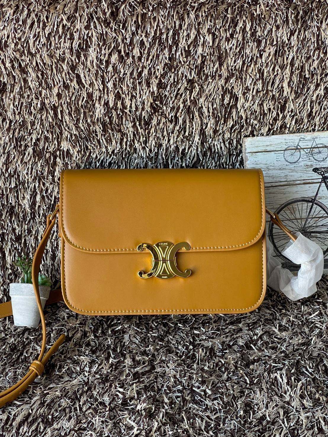 Celine MEDIUM TRIOMPHE BAG IN SHINY มีรูปทรงเป็นกล่องคล้ายกับกระเป๋า Classic Box แต่มีการออกแบบโลโก้ที่สะดุดตาแบบวินเทจ ด้วยดีไซน์ที่ดูโฉบเฉี่ยว แต่คงความคลาสสิคอย่างเต็มเปี่ยม ทำให้เป็นที่ดึงดูดความสนใจของสาวๆ สายสะพายสามารถปรับระดับได้ มีความคล่องตัวในก