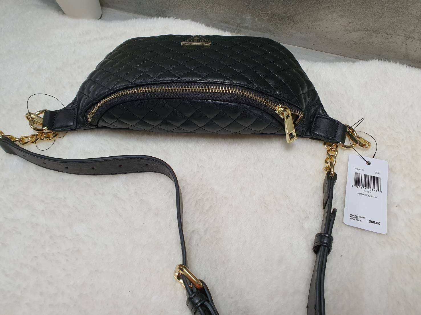 กระเป๋า Guess รุ่นนี้คาดเอว/คาดอก/สะพายข้างได้ครบทุกฟังก์ชั่น ด้านหน้าหนังเป็นลายตาราง ติดโลโก้แบรนด์รูปสามเหลี่ยมด้านหน้า เปิดปิดด้วยซิปยาว ด้านในเป็นช่องกว้างมีช่องซิปด้านใน ตัวกระเป๋าด้านหลังเป็นหนังเรียบ รุ่นนี้มีสายสะพายมา 2 เส้น เส้นแรกเป็นสายหนังปร