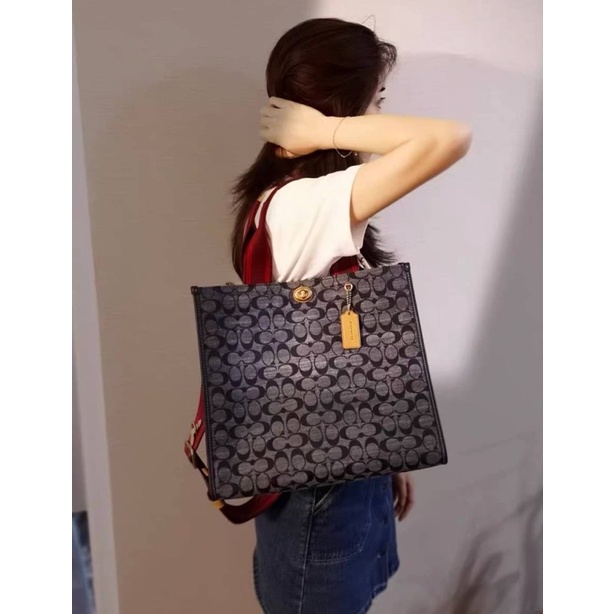 COACH Tote 34 In Signature Chambray หากคุณกำลังมองหากระเป๋าที่มีดีไซน์แปลกตา ไม่ค่อยเหมือนที่พบเห็นทั่วไป ต้องเป็นรุ่นนี้เลยค่ะ นอกจากจะผลิตจากผ้าแชมเบรย์ซึ่งมีน้ำหนักเบาแล้ว ยังให้สีสันคล้ายกับสียีนส์ สายสะพายและหูหิ้วสไตล์สปอร์ต ที่สำคัญยังมีหมุดปิดกระเ