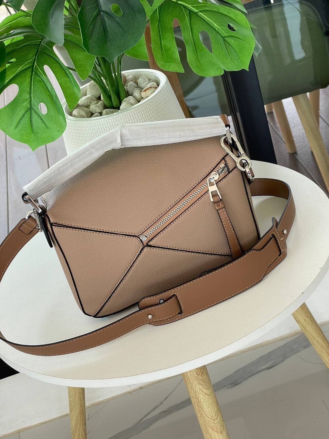 Loewe Puzzle Bag In Classic กระเป๋าทรง Puzzle นี้ออกแบบโดย Jonathan Anderson โดยได้รับแรงบันดาลใจในการออกแบบมาจากรูปทรงของลูกรักบี้ ดังนั้น จึงจะเห็นได้ว่าการตัดเย็บและรูปทรงของกระเป๋านั้นคล้ายคลึงกับลูกรักบี้ รูปทรงดูมินิมอลไม่ทิ้งคอนเซ็ปต์ของแบรนด์ สามา