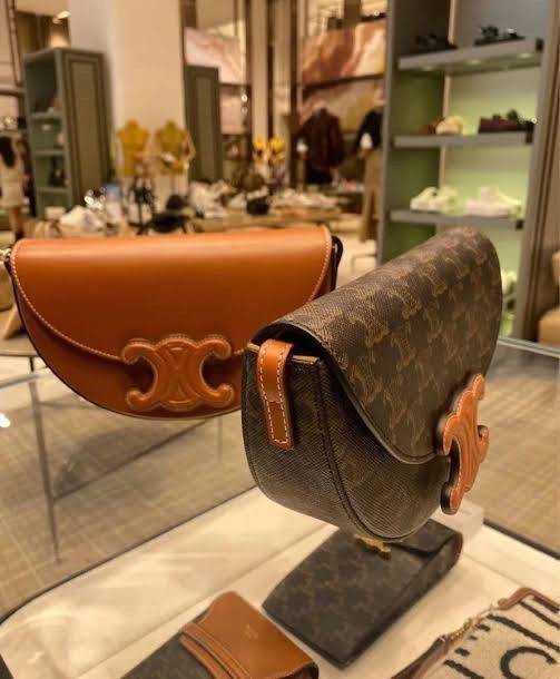 CELINE BESACE CUIR TRIOMPHE IN SMOOTH กระเป๋ารุ่นนี้นำเสนอในรูปทรงฮาล์ฟมูนที่ตอนนี้กำลังงมาแรง เปิดด้วยกระดุมแป๊กเพื่อเผยให้เห็นช่องภายในที่กว้างขวางและกระเป๋าด้านในแบบแบน คุณสมบัติที่โดดเด่นอีกอย่างของกระเป๋าอยู่ที่โลโก้ขนาดใหญ่ รูปทรงสะดุดตา สามารถสะพาย