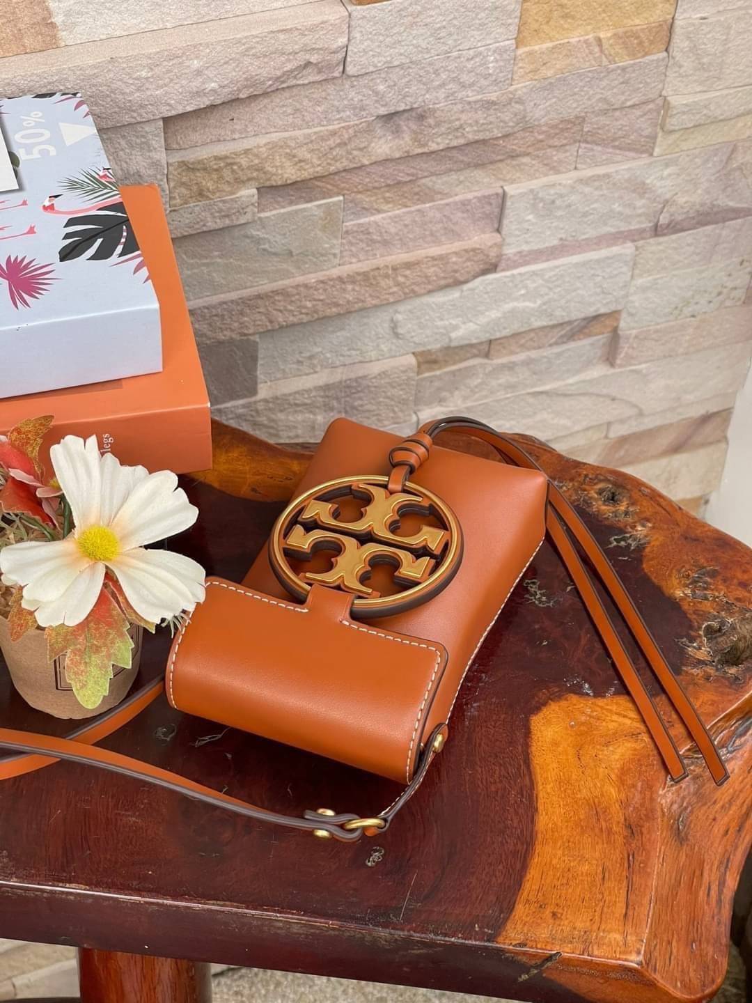 TORY BURCH MILLER METAL PHONE CROSSBODY อีกหนึ่งกระเป๋าใส่มือถือรุ่นฮิตที่เชื่อว่าหลาย ๆ คนต้องเคยเห็นผ่าน ๆ ตามาอย่างแน่นอน กับแบรนด์ Tory Burch ดีไซน์กระเป๋าทรงฝาพับแม่เหล็กใช้งานง่าย มาพร้อมดีเทล Logo แบรนด์โดดเด่นสีทองตัดกับหนังแกะสีดำ ดูหรูดูแพง! แต่