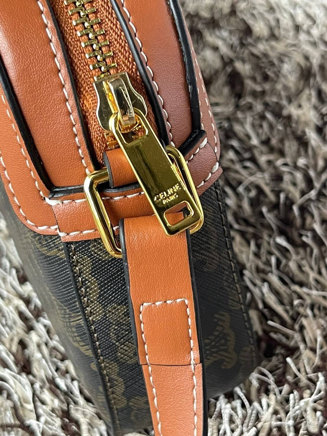 CELINE Triomphe Canvas Small Camera กระเป๋าสะพายไหล่สุดเก๋ใบนี้ผลิตจากผ้าใบเคลือบอย่างดีพร้อมขอบหนังสีน้ำตาล มาพร้อมสายสะพายหนังปรับระดับได้พร้อมฮาร์ดแวร์สีทองและซิปด้านบน ภายในบุด้วยผ้าสีน้ำตาล ลวดลาย triomphe อันเป็นเอกลักษณ์ของแบรนด์ และเป็นกระเป๋าสะพา