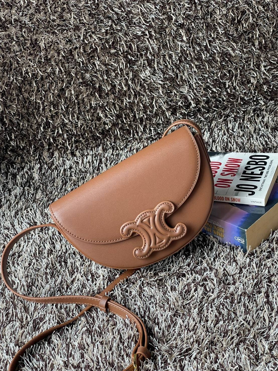 CELINE BESACE CUIR TRIOMPHE IN SMOOTH กระเป๋ารุ่นนี้นำเสนอในรูปทรงฮาล์ฟมูนที่ตอนนี้กำลังงมาแรง เปิดด้วยกระดุมแป๊กเพื่อเผยให้เห็นช่องภายในที่กว้างขวางและกระเป๋าด้านในแบบแบน คุณสมบัติที่โดดเด่นอีกอย่างของกระเป๋าอยู่ที่โลโก้ขนาดใหญ่ รูปทรงสะดุดตา สามารถสะพาย