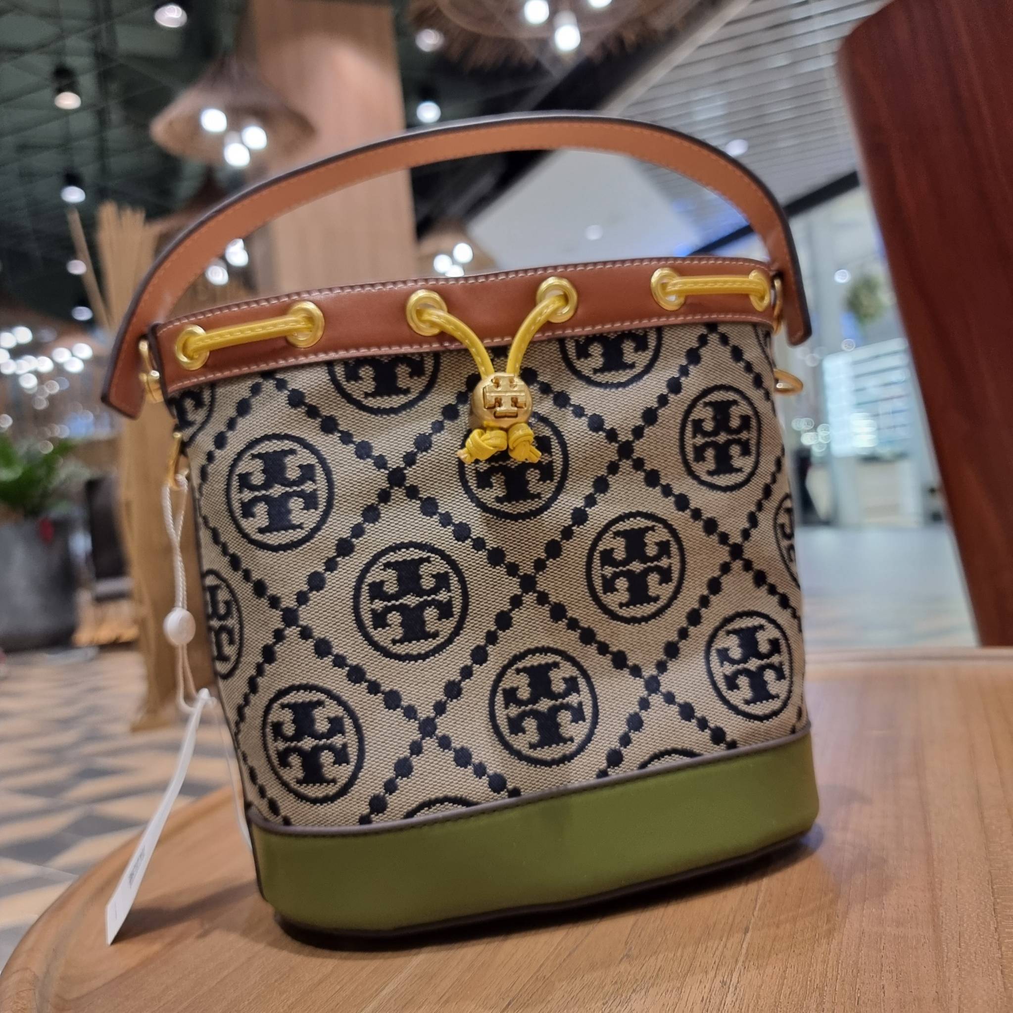 TORY BURCH T MONOGRAM COLORBLOCK JACQUARD BUCKET BAG ไอเท็มใหม่ที่ใครๆก็รอ กระเป๋าบัคเก็ตทรงสวย ที่ยังคงให้ความโดดเด่นด้วยลวดลายเอกลักษณ์ เพิ่มเติมดีไซน์บล็อคสี ตัดกันได้อย่างลงตัว ถักทอบนวัสดุ woven jacquard ลายคมชัด สลับส่วนของหนังแท้ ภายในเป็นช่องโล่งก
