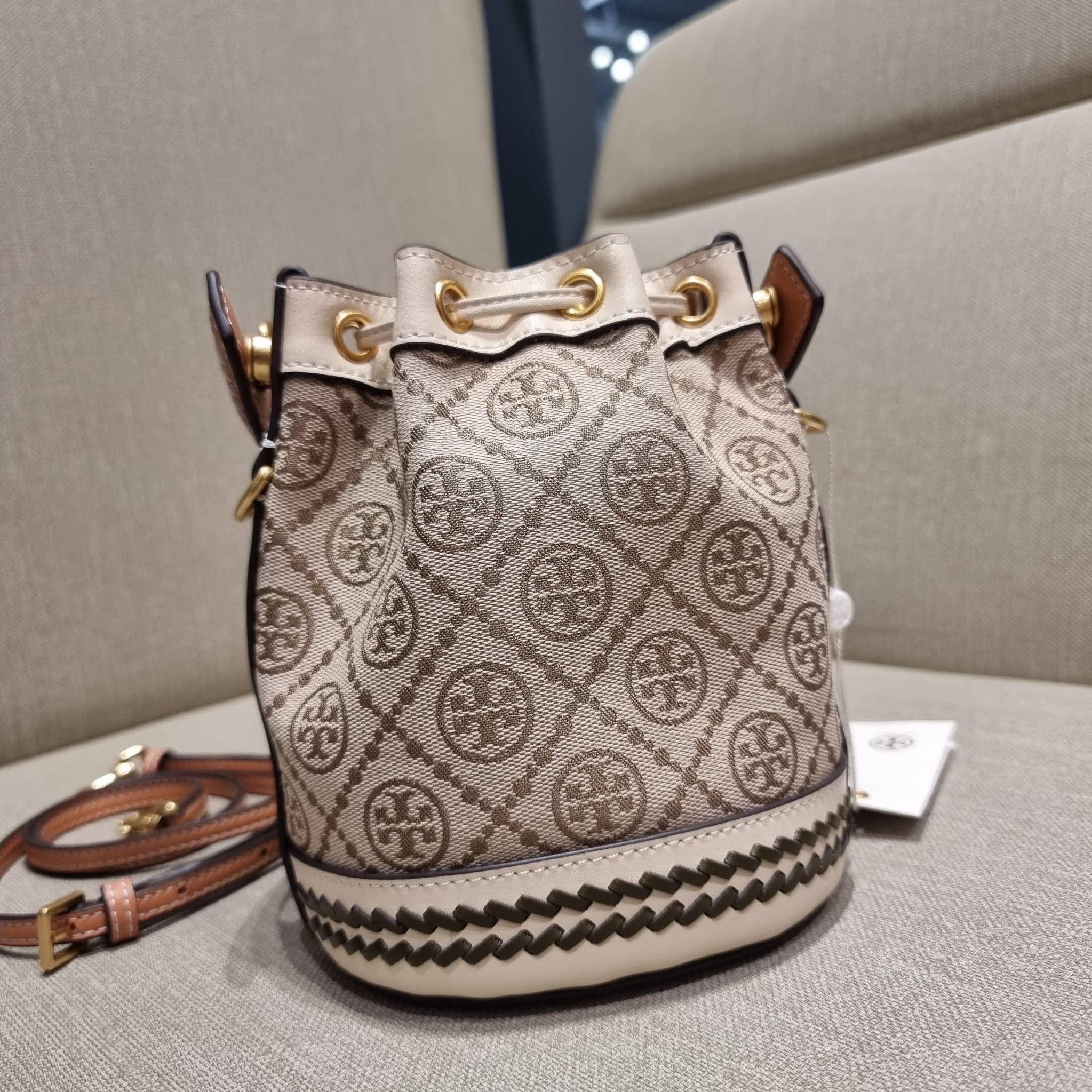 TORY BURCH MINI T MONOGRAM FLORAL BUCKET BAG คอลเลคชั่นใหม่ พร้อมเสิร์ฟความสวยให้ถึงบ้าน!! กระเป๋าบัคเก็ตทรงยอดนิยม ไซส์มินิ ดีไซน์ใหม่ล่าสุด สไตล์งานคราฟ มีลูกเล่นประดับดอกไม้กับตัวกระเป๋า และตัวรูดสาย วัสดุผ้า jacquard ตัดสลับหนังแท้ หูจับและขอบกระเป๋าต