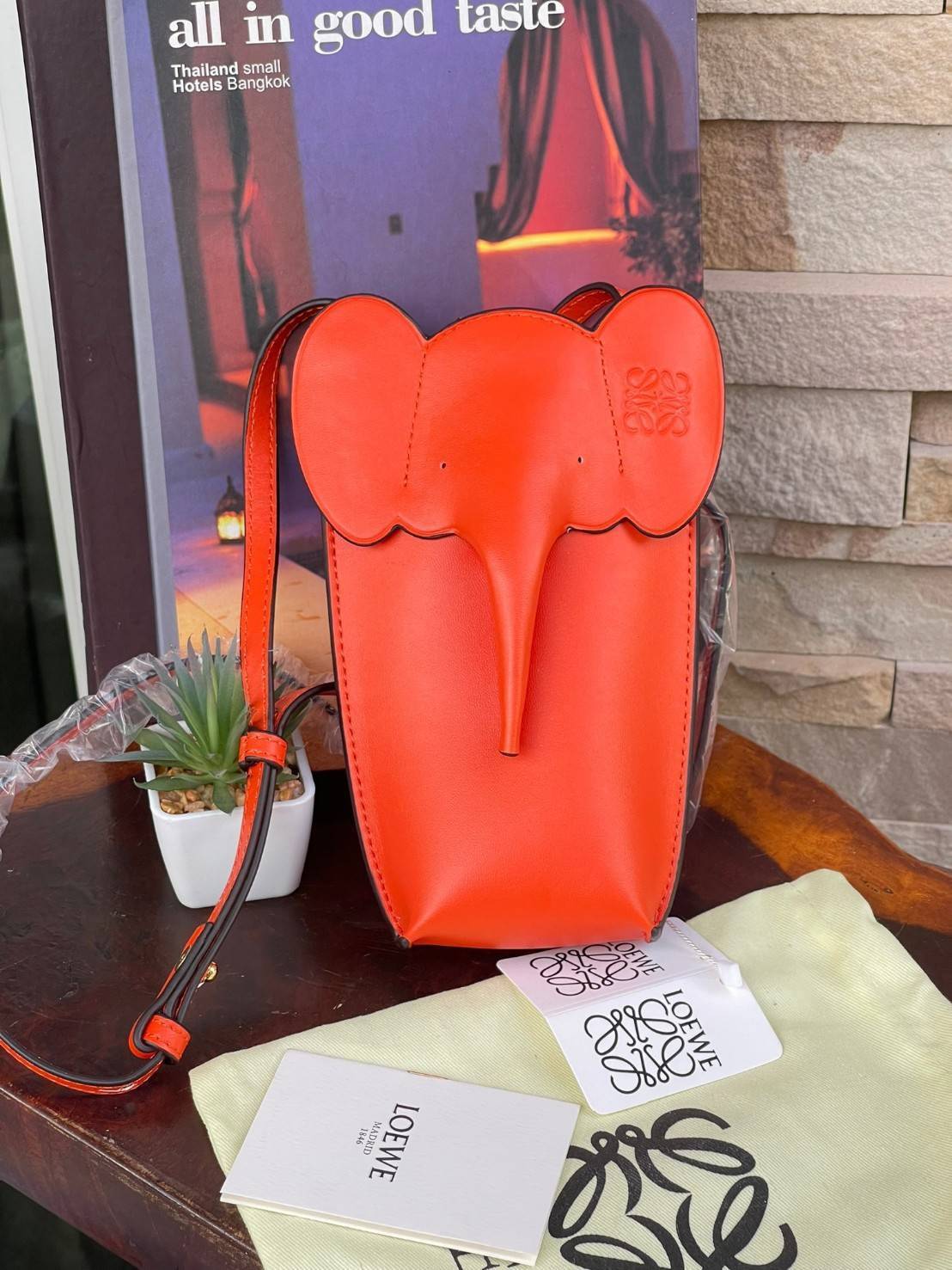 Loewe Leather Elephant Phone Holder แบรนด์หรูจากประเทศสเปนอย่าง โลเอเว่ (LOEWE) หลายๆคนคงนึกถึงกระเป๋ารูปทรงช้างขนาดเล็ก ที่เป็นเหมือนหนึ่งในซิกเนเจอร์ของแบรนด์ มีทั้งแบบสะพายข้าง แบบถือ รวมไปถึงในแบบเครื่องหนังชิ้นเล็กอย่างกระเป๋าใส่มือถือรุ่นนี้ ผลิตจาก