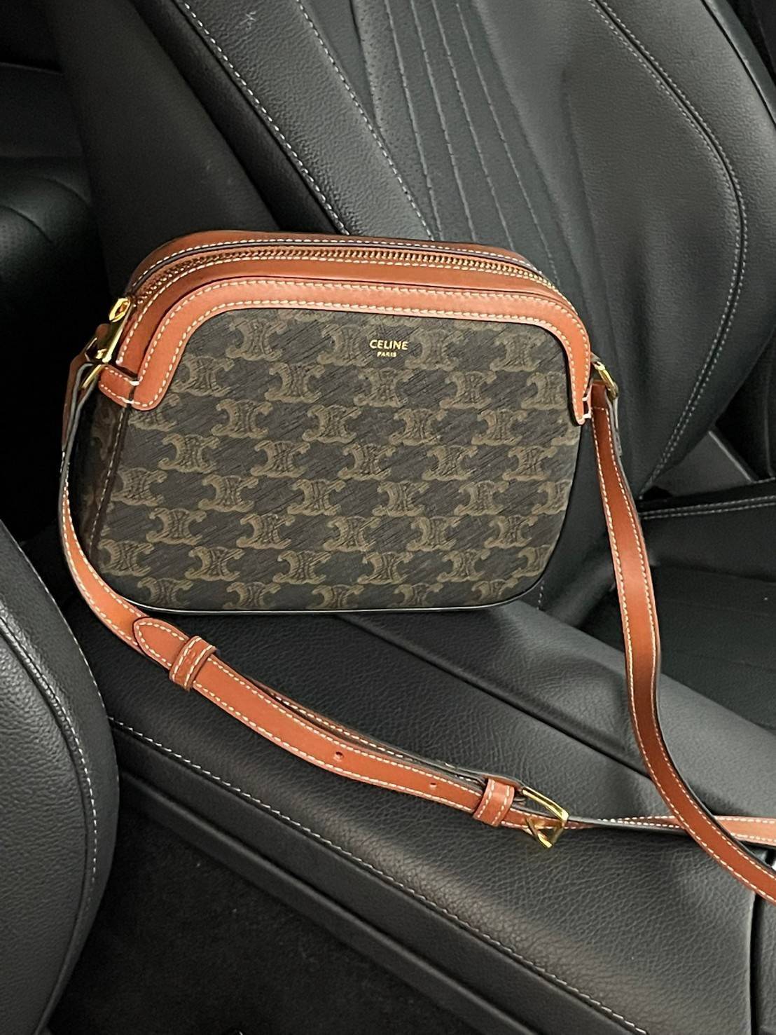 CELINE Triomphe Canvas Small Camera กระเป๋าสะพายไหล่สุดเก๋ใบนี้ผลิตจากผ้าใบเคลือบอย่างดีพร้อมขอบหนังสีน้ำตาล มาพร้อมสายสะพายหนังปรับระดับได้พร้อมฮาร์ดแวร์สีทองและซิปด้านบน ภายในบุด้วยผ้าสีน้ำตาล ลวดลาย triomphe อันเป็นเอกลักษณ์ของแบรนด์ และเป็นกระเป๋าสะพา