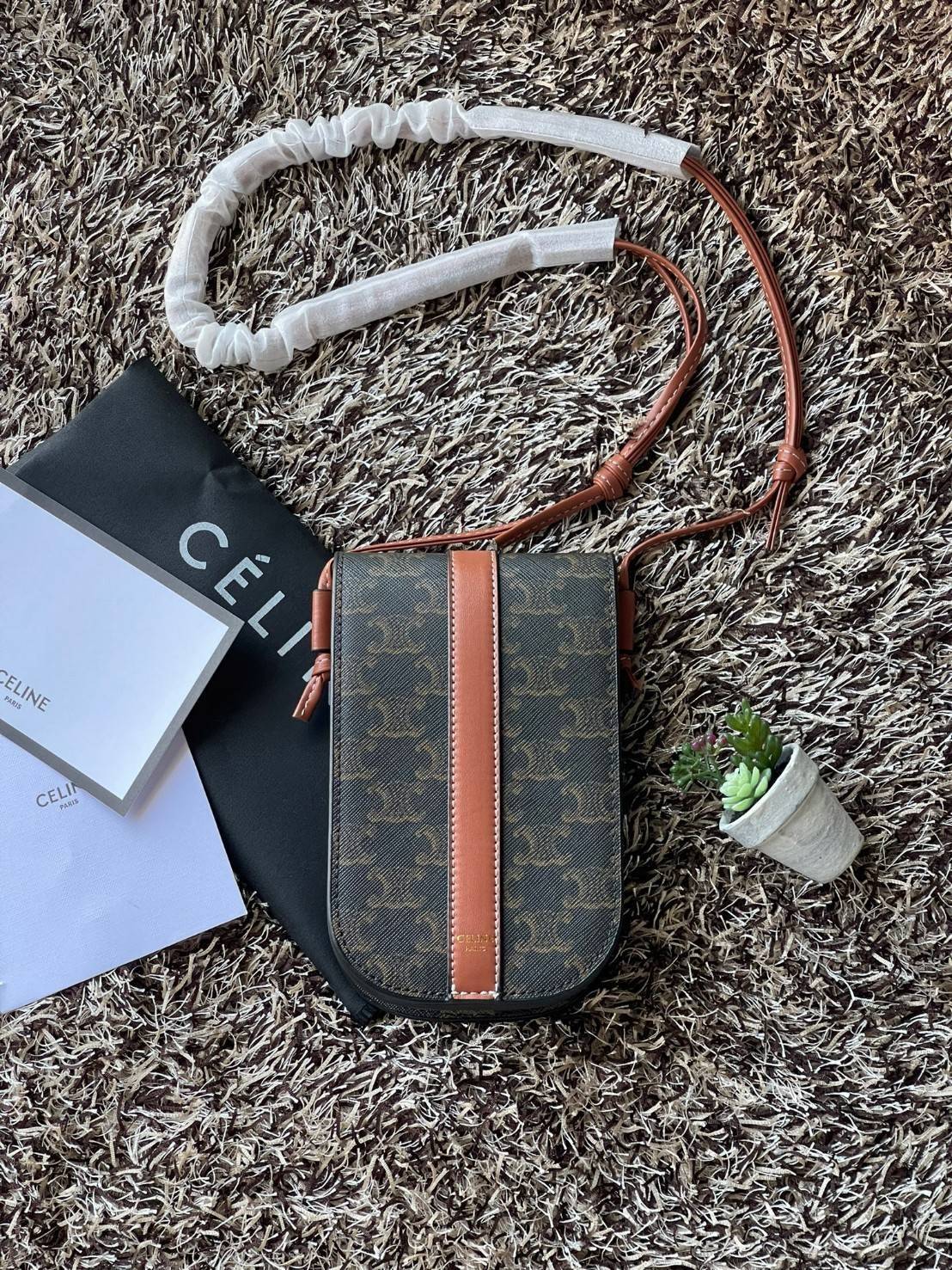 Celine Phone Pouch in Triomphe Canvas กระเป๋าใส่โทรศัพท์รุ่นนี้ มีดีไซน์ดูเรียบง่าย แต่ดูหรูหราด้วยลวดลาย Triompe ที่แสดงถึงความเป็นเอกลักษณ์ของ celine ช่องหลักที่มีความกว้าง สามารถใส่โทรศัพท์มือถือ ธนบัตร บัตรต่าง ๆ และของจุกจิกชิ้นเล็ก ๆ ได้แบบจุใจ หรือ