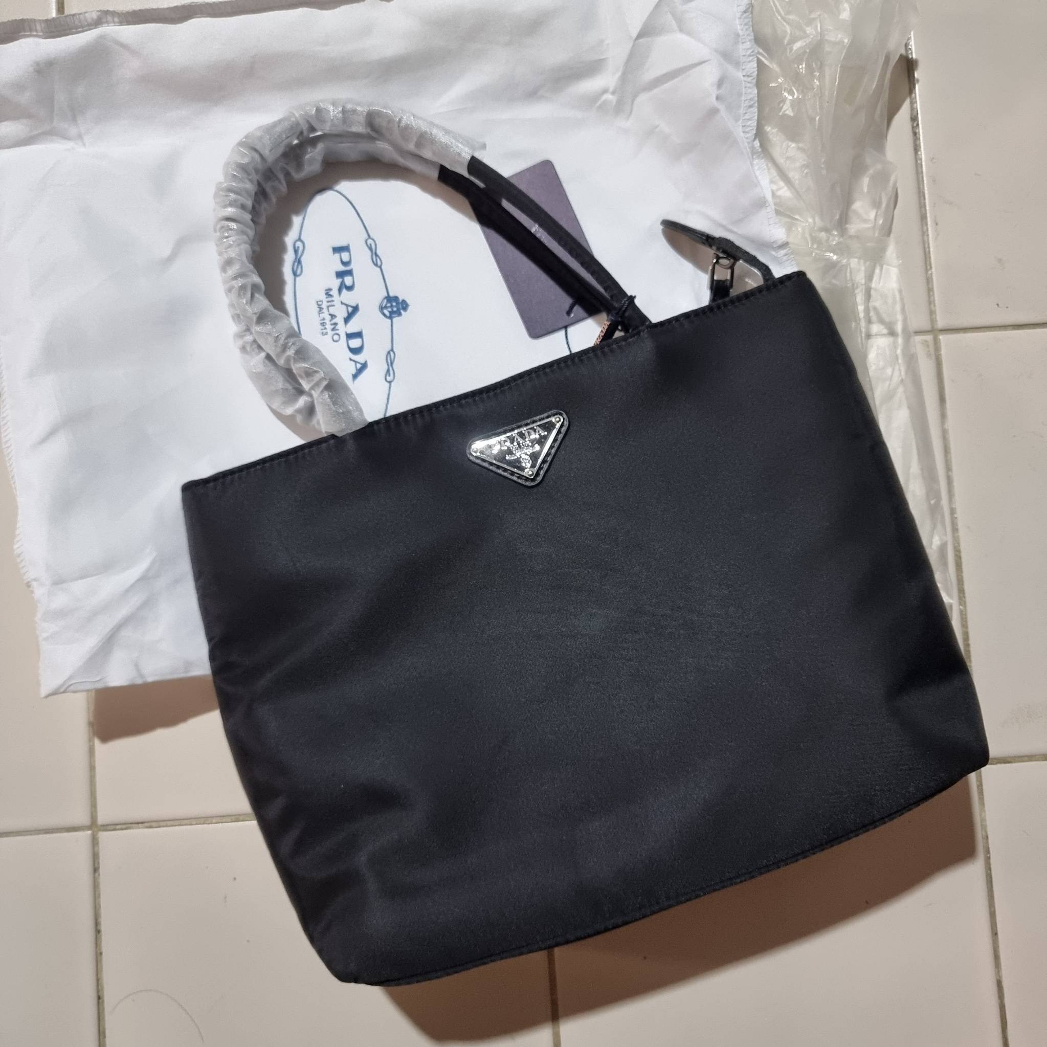 PRADA RE-NYLON TESUTO TOTE BAG กระเป๋าทรงช้อปปิ้ง ขนาดกำลังสวย รุ่นหายาก ขายดีตลอดกาล!!ด้วยรูปทรงที่ใช้งานง่ายและสะดวก ทำให้ครองใจทั้งสาวๆและหนุ่มๆได้ไม่ยาก วัสดุผ้าไนล่อนคุณภาพ พร้อมใบลูก ไว้ใส่เหรียญ ใส่กุญแจได้สารพัด ปากกระเป๋ามีซิปปิดกันของหล่น ภายในเ