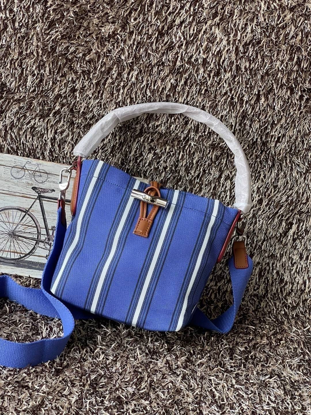 LONGCHAMP ROSEAU ESSENTIAL RAYÉ Bucket bag S - Blue สำหรับใครที่ต้องการกระเป๋าแบบใช้งานได้ในหลาย ๆ โอกาส สีสันกระเป๋าสามารถแมทช์ได้ง่ายกับเสื้อผ้า Longchamp รุ่นนี้สามารถตอบโจทย์ เป็นกระเป๋าที่ขนาดกำลังพอดี