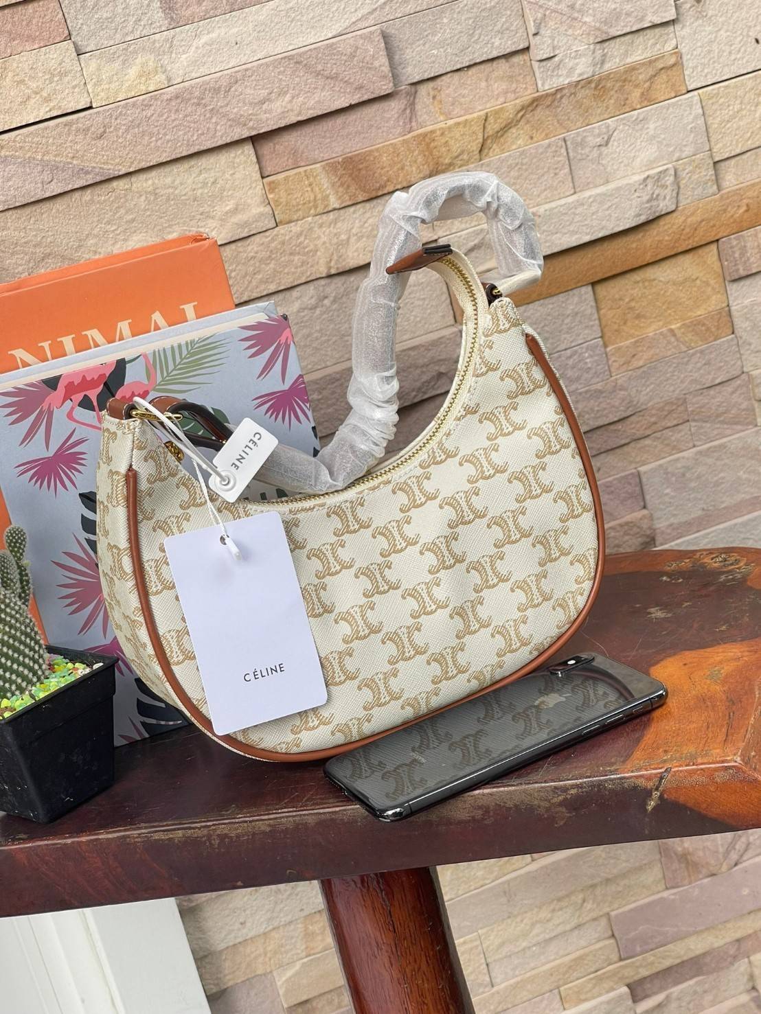 CELINE Vintage Classic Ava bag 1 ใน คอลเลคชั่น “Triomphe Canvas” มาพร้อมสายสะพายไหล่ที่ปรับความยาวได้ และเนื่องจากช่วงล่างของกระเป๋ามีขนาดใหญ่กว่าช่วงบน จึงทำให้ไม่เสียทรงเมื่อเราใส่สิ่งของอย่างกระเป๋าสตางค์หรือโทรศัพท์มือถือ หากดูภาพรวมแล้ว รุ่นนี้ออกแนว