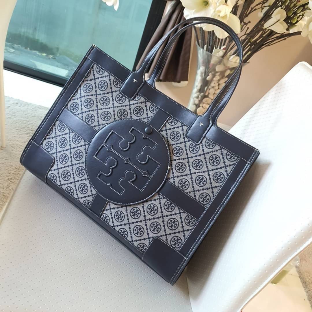 OUTTLET 】TORY BURCH TOTE BAG วัสดุ CANVAS ทั้งใบตัดด้วยหนังแท้สี NAVY ตัวกระเป๋าตั้งอยู่ทรงสวย แต่งโลโก้แบรนด์ด้านหน้า ด้านข้างมีกระดุม สามารถขยายทรงได้ ด้านในเปิดปิดด้วยกระดุมแม่เหล็ก ช่องกว้างหลักหนึ่งช่องและช่องซิปอีกช่อง สามารถใส่กระเป๋าสตางค์ยาว สมุด