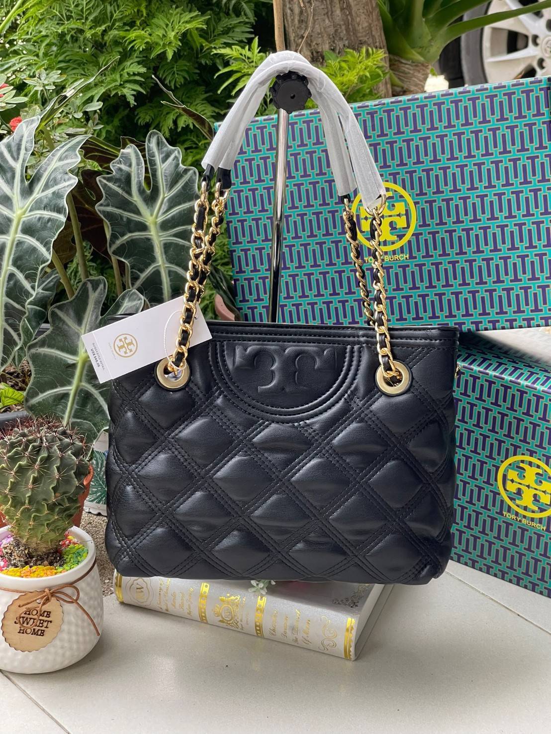 Tory Burch Fleming Soft Small Tote Bag เป็นกระเป๋าสะพายไหล่น่ารัก ๆ สักใบที่มีดีไซน์โดดเด่น สะดุดตา ใน Collection เรียกได้ว่าขายดีอันดับต้น ๆ ของแบรนด์ ใช้ได้ในลุคช์ทางการและกึ่งทางการ ดีเทลการตัดเย็บพิมพ์ลายนูนคู่กับแพทเทิร์นสี่เหลี่ยมทรงเพชร ที่ช่วยเพิ่
