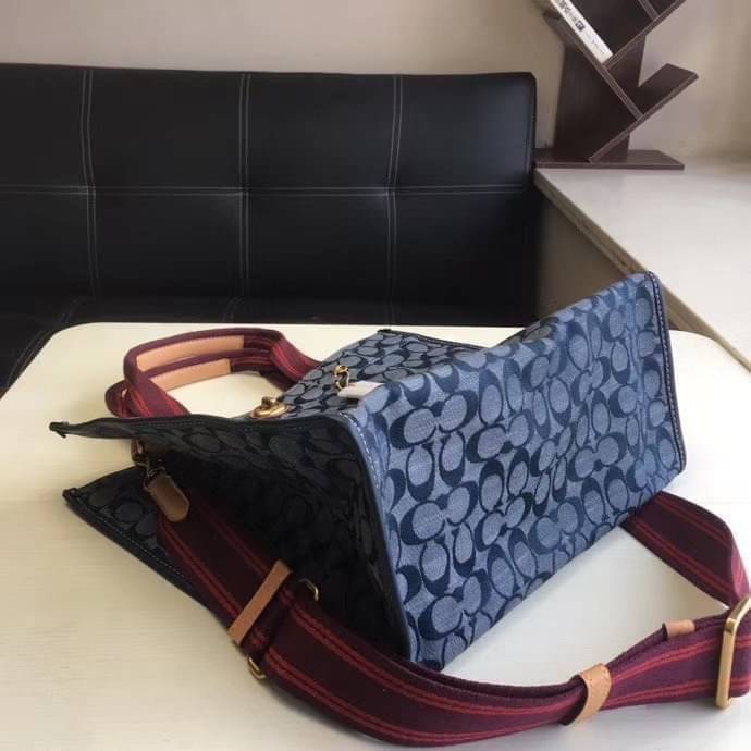 COACH Tote 34 In Signature Chambray หากคุณกำลังมองหากระเป๋าที่มีดีไซน์แปลกตา ไม่ค่อยเหมือนที่พบเห็นทั่วไป ต้องเป็นรุ่นนี้เลยค่ะ นอกจากจะผลิตจากผ้าแชมเบรย์ซึ่งมีน้ำหนักเบาแล้ว ยังให้สีสันคล้ายกับสียีนส์ สายสะพายและหูหิ้วสไตล์สปอร์ต ที่สำคัญยังมีหมุดปิดกระเ