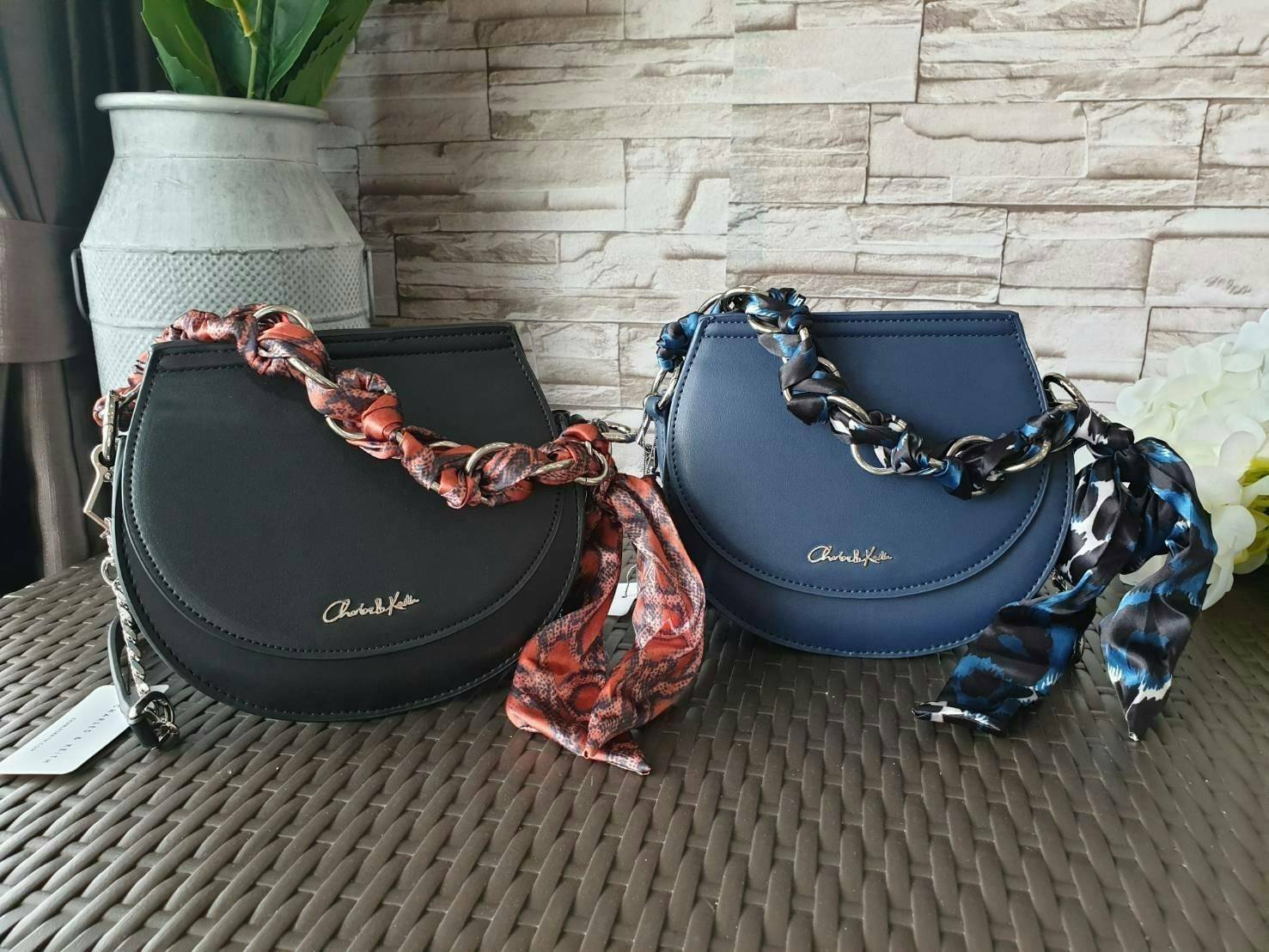 CHARLES & KEITH รุ่น LEATHER SATIN SCARF CROSSBODY BAG SL2-50150828 ราคาปกติช้อป ( ฿3,590.00 ) กระเป๋าถือ และ สะพาย ทรงโค้งมน หนังเรียบ ตั้งอยู่ทรง ด้านหน้าติดโลโก้แบรนด์ อะไหล่เงิน หูจับสายกระเป๋าร้อยเข้ากับห่วงเหล็กกลมๆ ด้วยผ้าลายสวยงามผูกเป็นโบว์เก๋ๆ ถ