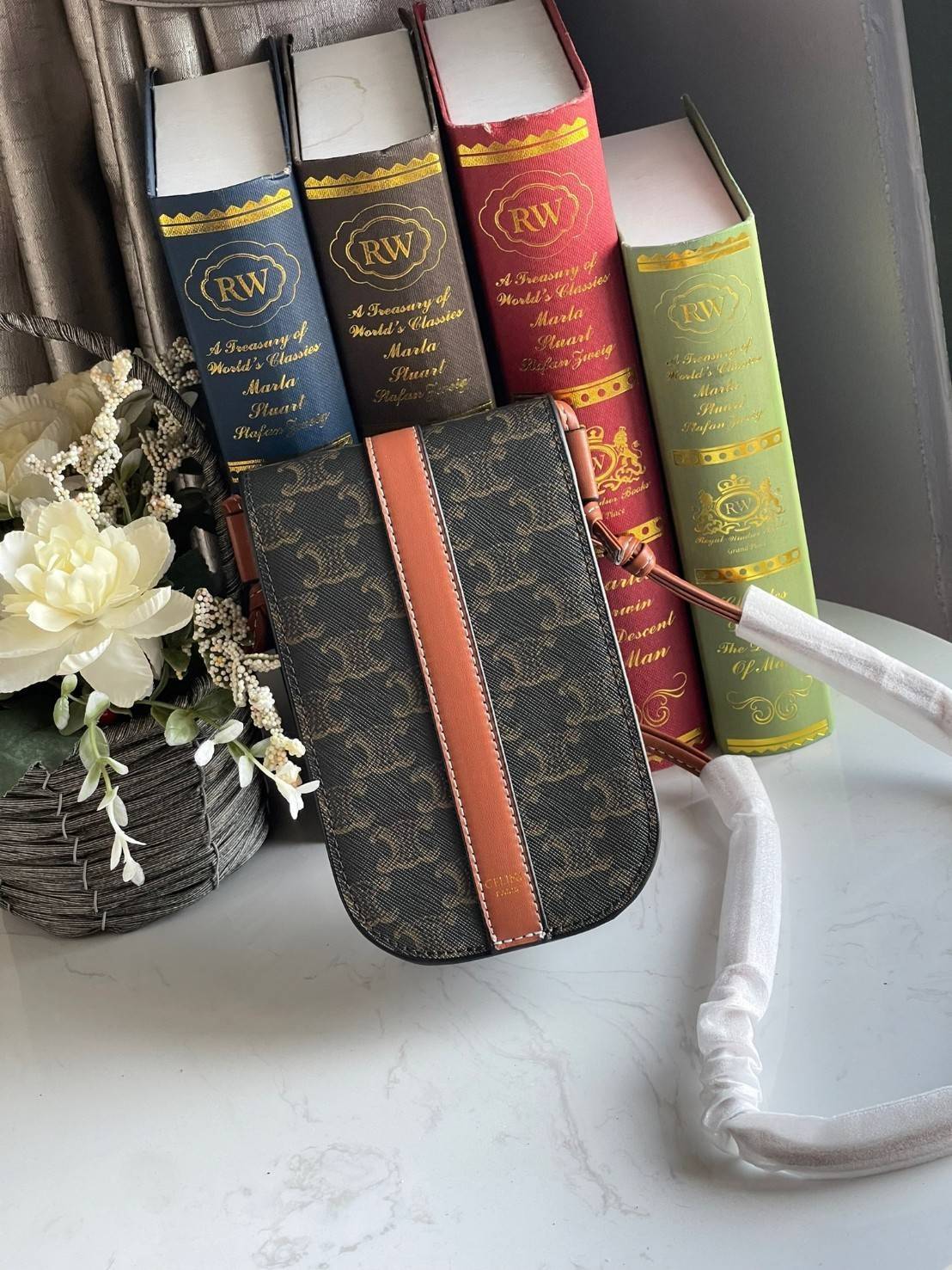 Celine Phone Pouch in Triomphe Canvas กระเป๋าใส่โทรศัพท์รุ่นนี้ มีดีไซน์ดูเรียบง่าย แต่ดูหรูหราด้วยลวดลาย Triompe ที่แสดงถึงความเป็นเอกลักษณ์ของ celine ช่องหลักที่มีความกว้าง สามารถใส่โทรศัพท์มือถือ ธนบัตร บัตรต่าง ๆ และของจุกจิกชิ้นเล็ก ๆ ได้แบบจุใจ หรือ