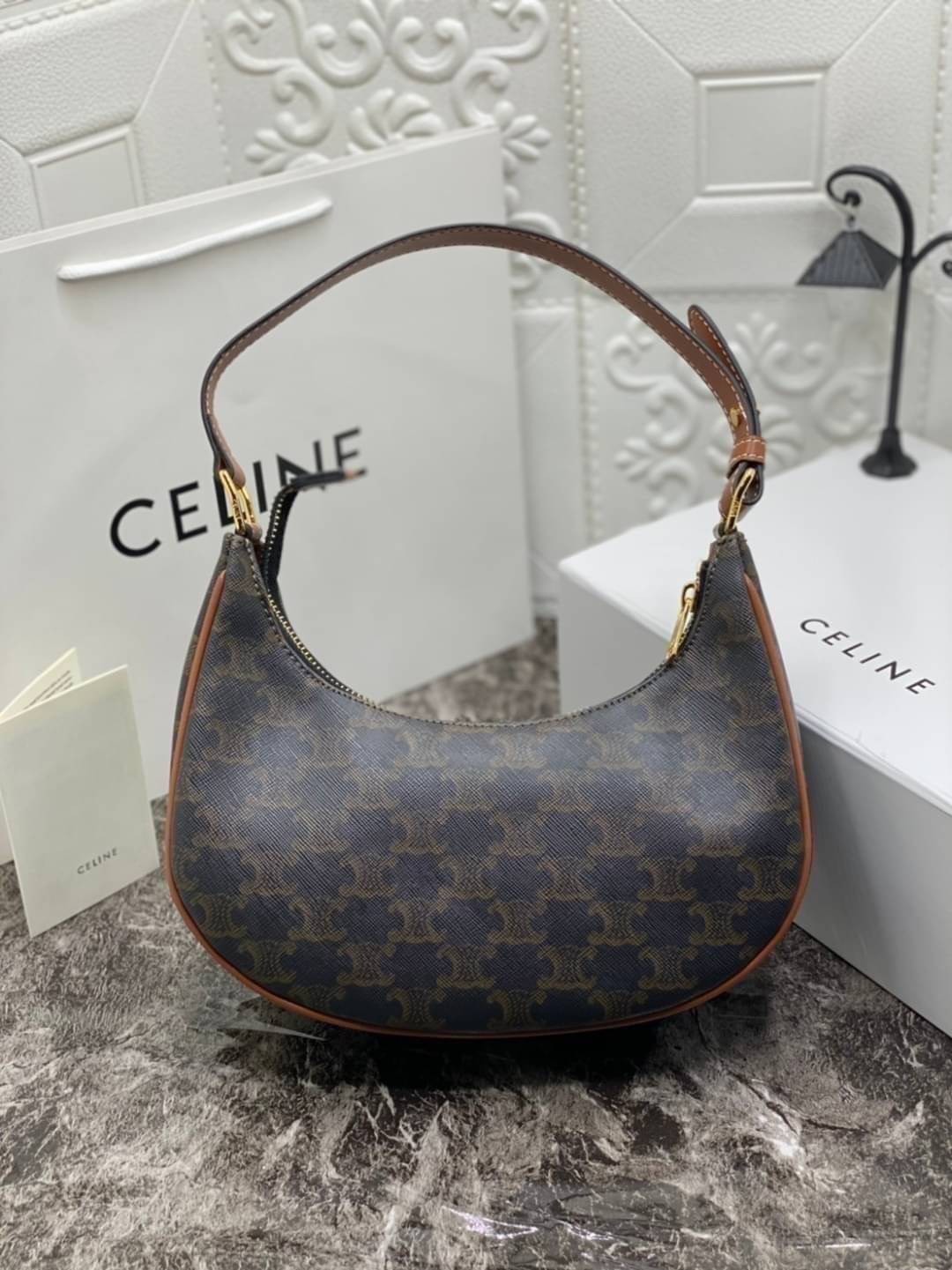 หนังแท้ CELINE AVA / CELINE Vintage Classic Ava bag 1 ใน คอลเลคชั่น “Triomphe Canvas” มาพร้อมสายสะพายไหล่ที่ปรับความยาวได้ และเนื่องจากช่วงล่างของกระเป๋ามีขนาดใหญ่กว่าช่วงบน จึงทำให้ไม่เสียทรงเมื่อเราใส่สิ่งของอย่างกระเป๋าสตางค์หรือโทรศัพท์มือถือ หากดูภาพ