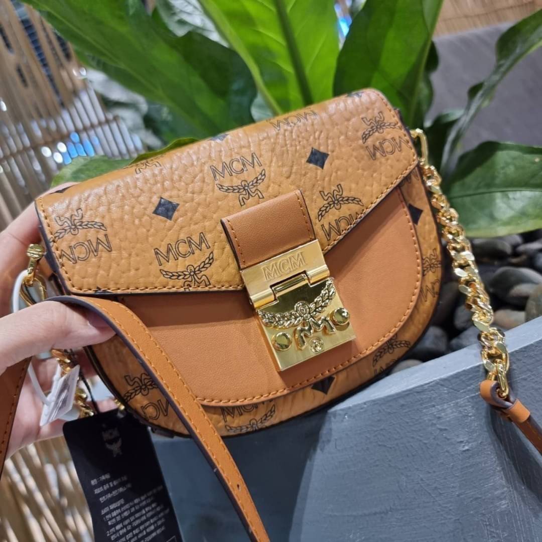 M.C.M MINI PATRICIA CROSSBODY IN VISETOS กระเป๋าสะพายไซส์มินิ แรงดีไม่มีตกน้า คอลเลคชั่นนี้ดีไซน์แปลกใหม่ ทรงโค้งมน สวยหรู ด้านข้างตกแต่งหมุดทองรอบใบ วัสดุตัวกระเป๋าเป็นหนังแคนวาสคุณภาพดี ภายในเป็นหนังกลับสีส้มโดดเด่นเป็นเอกลักษณ์ มีช่องใส่บัตรแยกให้ เปิด
