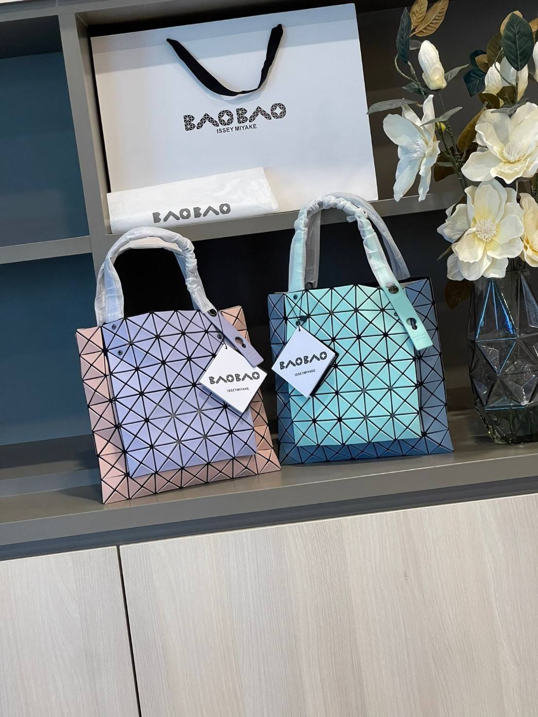 Baobao Issey Miyake Prism Kangaroo tote bag กระเป๋าถือทรงโท้ทที่ประดิษฐ์ขึ้นอย่างเชี่ยวชาญในญี่ปุ่น มาพร้อมแผงเรขาคณิตสำหรับการออกแบบที่ได้รับแรงบันดาลใจจากกระดาษพับ ซิลลูเอทอันเป็นเอกลักษณ์นี้ปิดท้ายด้วยสายรัดแบบอสมมาตร มีการพัฒนาโครงสร้างทรงสามเหลี่ยมเพ