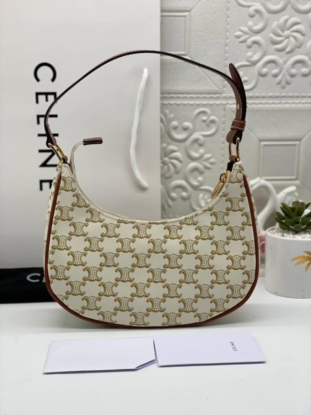 หนังแท้ CELINE AVA / CELINE Vintage Classic Ava bag 1 ใน คอลเลคชั่น “Triomphe Canvas” มาพร้อมสายสะพายไหล่ที่ปรับความยาวได้ และเนื่องจากช่วงล่างของกระเป๋ามีขนาดใหญ่กว่าช่วงบน จึงทำให้ไม่เสียทรงเมื่อเราใส่สิ่งของอย่างกระเป๋าสตางค์หรือโทรศัพท์มือถือ หากดูภาพ