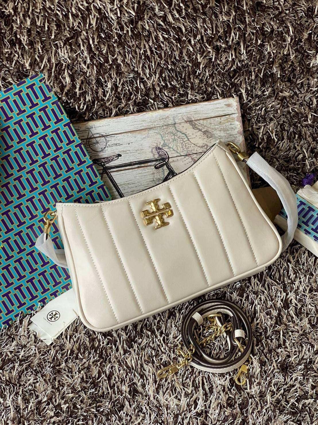 Tory burch Kira logo-plaque crossbody bag กระเป๋า Kira ของ Tory Burch เป็นส่วนหนึ่งของคอลเล็กชั่นที่โดดเด่น และมีหลายรุ่นด้วยกัน โดยมีป้ายโลโก้ Double T ของแบรนด์อยู่ตรงกลาง มีความเรียบง่ายแต่ยังคงความหรูหราโดดเด่นด้วยวัสดุบุผิว ป้ายโลโก้สีทอง สายสะพายโซ่