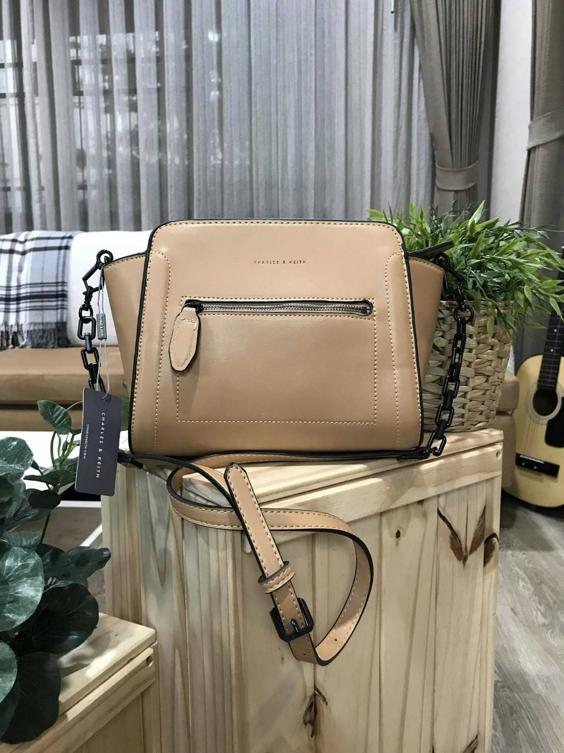 CHARLES & KEITH TRAPEZE CROSSBODY BAG กระเป๋าถือหรือสะพายดีไซน์ยอดนิยมหนังอยู่ทรงสวย ด้านหน้าสกรีนโลโก้ และมี 1 ช่องซิป เปิดปิดด้วยซิป ภายในมีช่องใส่ของ และช่องซิปเล็ก ใส่กระเป๋าสตางค์ใบยาว มือถือ ของใช้ได้เยอะ พร้อมสายสะพายยาวโซ่ต่อหนังปรับได้ถอดได้ มีหม