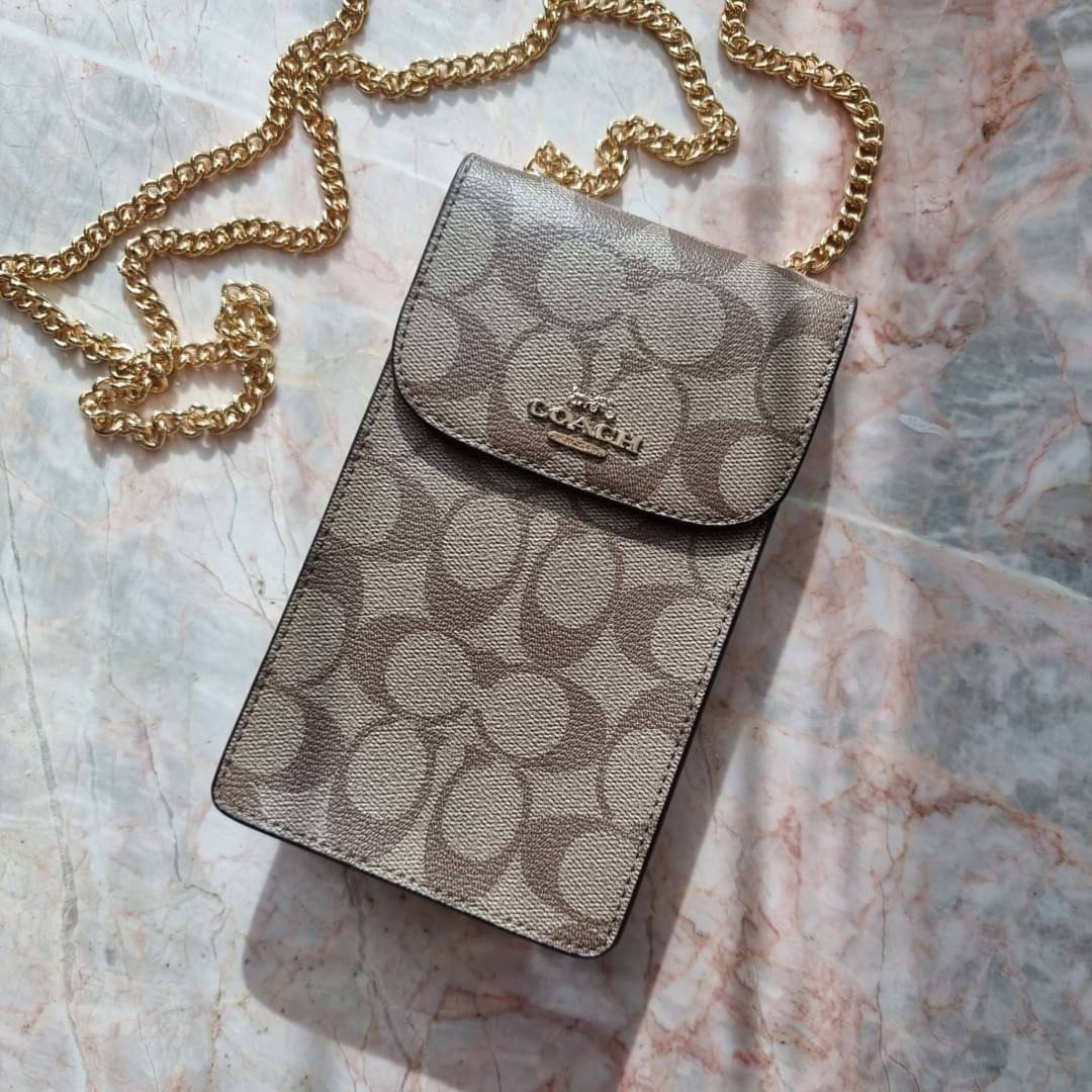 COACH NORTH/SOUTH PHONE CROSSBODY IN SIGNATURE CANVAS F55636 F39955 สุดคลาสสิคกับกระเป๋าสะพายเอนกประสงค์ Case phone ใส่โทรศัพท์มือถือได้ทุกรุ่น ดีไซน์ลายเอกลักษณ์ วัสดุหนังแคนวาสเคลือบลาย ฝาและภายในเป็นหนังสังเคราะห์เรียบ เปิด-ปิดด้วยกระดุม สายสะพายยาวประ