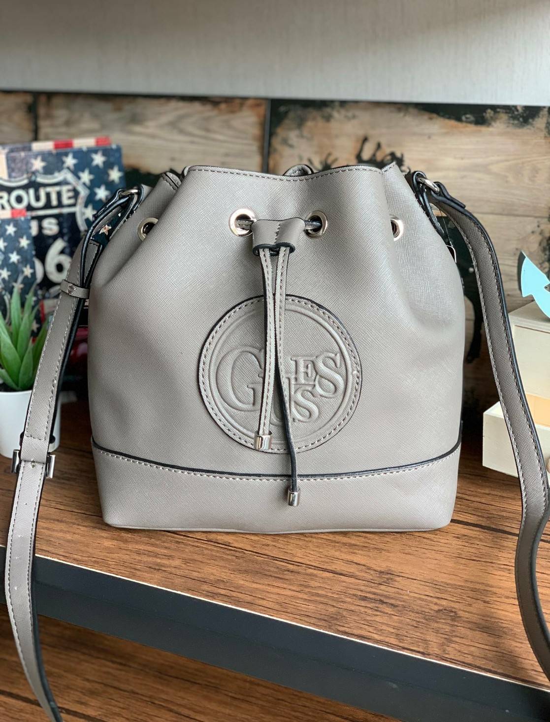 Guess Drawstring Bucket Bag กระเป๋าสะพายขนาดกลาง วัสดุลายหนังsaffiano ฐานกว้างตั้งอยู่ทรง มีซิกเนเจอร์ที่ด้านหน้าเป็นโลโก้ตัวนูน เปิดปิดแบบหูรูดและกระดุมแม่เหล็ก มีช่องใช้งานหลายข่อง สายสะพายปรับได้แบบเข็มขัด สวยแบบมีดีเทลเก๋ๆ สะพายเที่ยวระหว่างวันได้สบาย