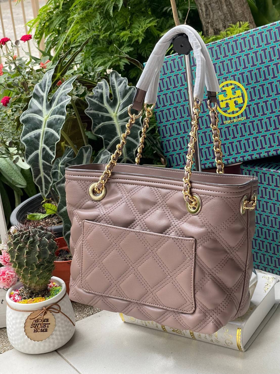 Tory Burch Fleming Soft Small Tote Bag เป็นกระเป๋าสะพายไหล่น่ารัก ๆ สักใบที่มีดีไซน์โดดเด่น สะดุดตา ใน Collection เรียกได้ว่าขายดีอันดับต้น ๆ ของแบรนด์ ใช้ได้ในลุคช์ทางการและกึ่งทางการ ดีเทลการตัดเย็บพิมพ์ลายนูนคู่กับแพทเทิร์นสี่เหลี่ยมทรงเพชร ที่ช่วยเพิ่
