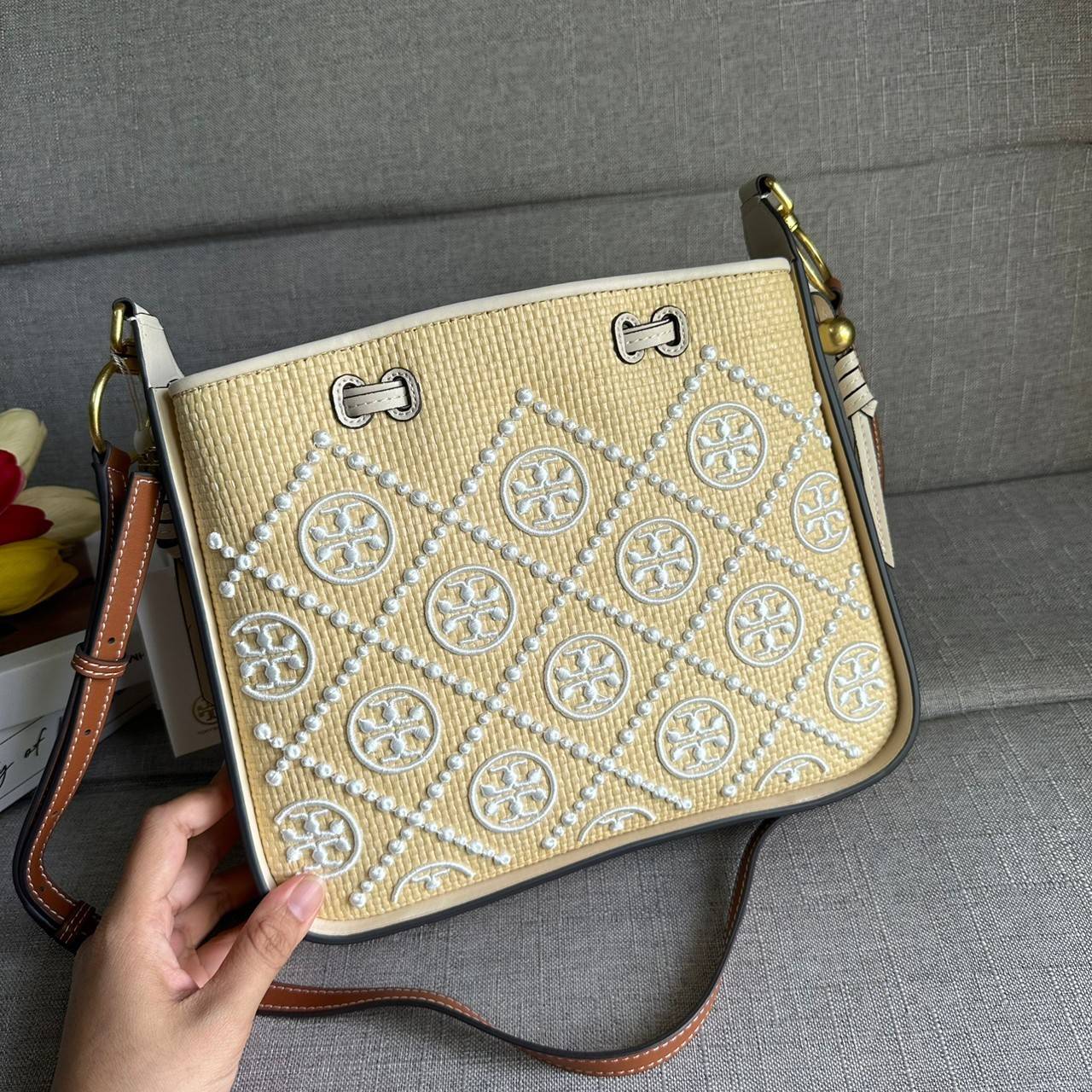 TORY BURCH T Monogram Straw Bell Bag กระเป๋าสะพายข้างรุ่นคลาสสิกที่ได้แรงบันดาลใจจากการควิลท์แบบดั้งเดิมของเพนซิลเวเนีย คอลเลกชันบ่งบอกถึงความมีสไตล์เหนือกาลเวลา รูปทรงเรียวโดดเด่น ปักทอลายแบรนด์อย่างสวยงาม เปิด ปิดด้วยเชือกรูด ด้านในช่องโล่งกว้าง ซับในผ้
