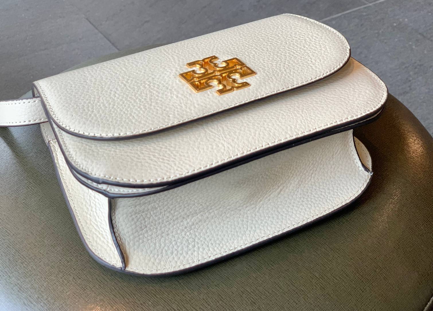 TORY BURCH BRLTTEN SMALL SADDLE BAG / Tory Burch Britten Flap Shoulder Bag กระเป๋าสะพายข้าง วัสดุหนังแกะแท้ ด้านหน้าประดับโลโก้แบรนด์ เปิด-ปิดกระเป๋าแบบกระดุมแป็กแม่เหล็กแน่นหนา ภายในมีช่องหลัก ใส่กระเป๋าเงินใบกลาง มือถือได้ทุกรุ่น มีช่องแยกใส่ของจุกจิกอี