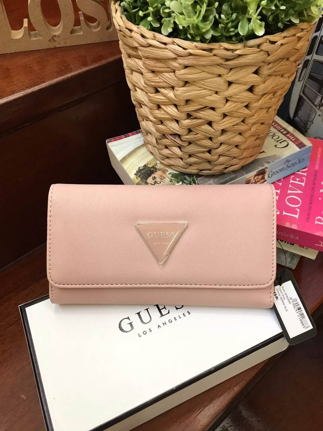 GUESS FACTORY WOMEN'S LONG WALLET กระเป๋าสตางค์ทรงยาวแบบสามพับ วัสดุหนังลายsaffiano เปิดปิดด้วยกระดุมสะดวกใช้ ภายในมีทั้งช่องซิปใส่เหรียญ ช่องใส่ธนบัตรและช่องใส่บัตรหลายช่องและช่องใส่รูปแยกเป็นสัดส่วน ด้านหน้ามีโลโก้แบรนด์ทรงสามเหลี่ยม ด้านหลังมี1ช่อ